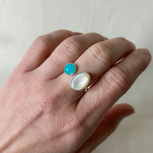 White oval stone ring with smaller blue stone on a gray background