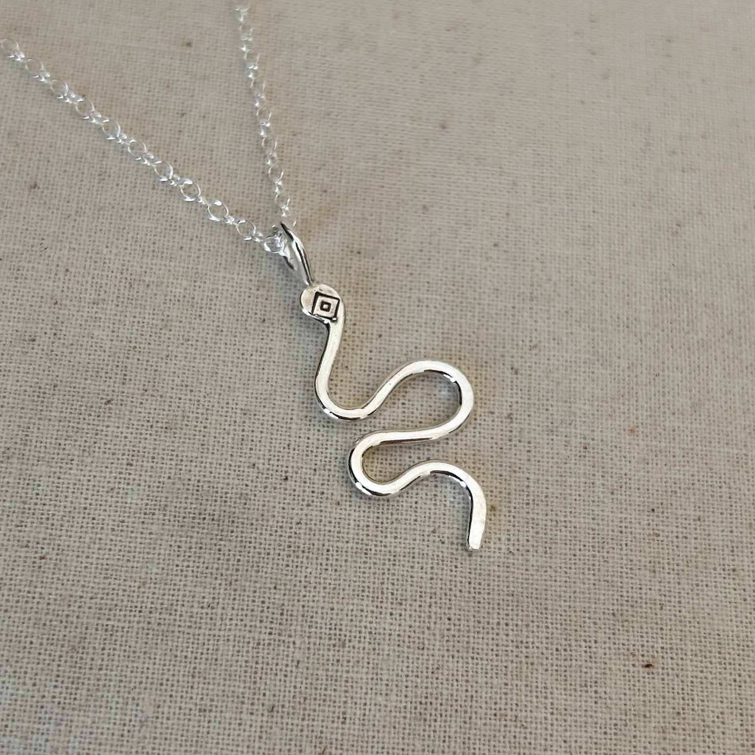 High polished Argentium silver snake pendant against grey background