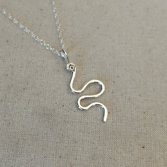 High polished Argentium silver snake pendant against grey background