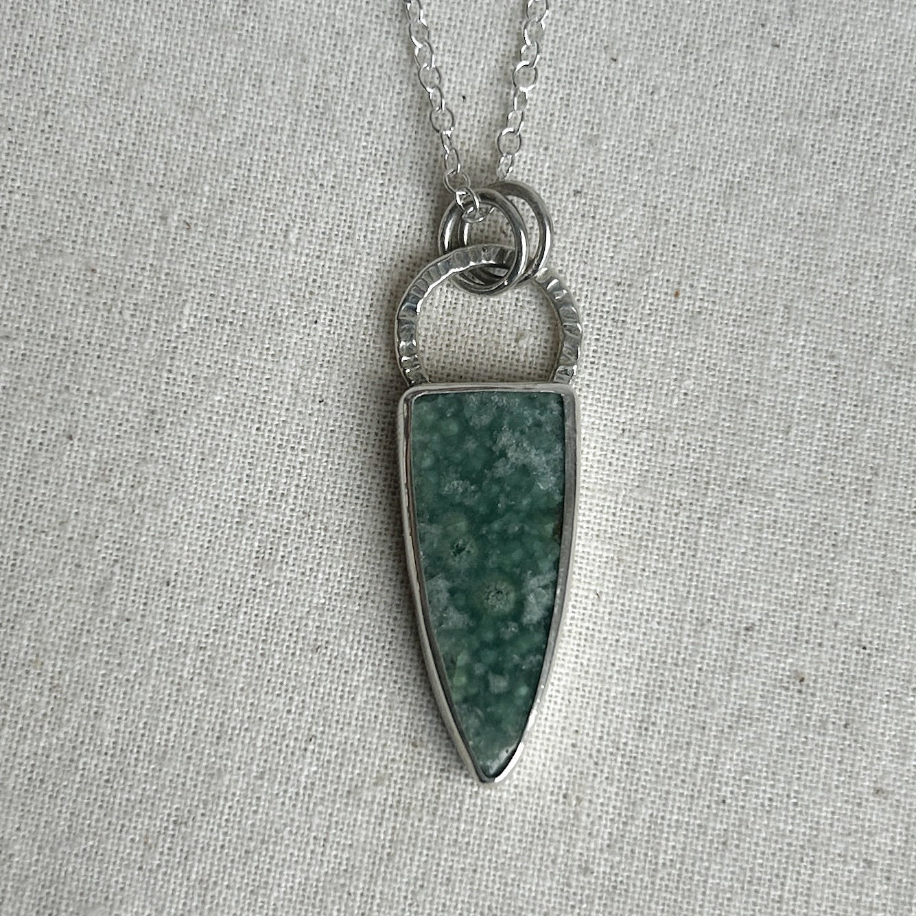 Green shield-like pendant on silver chain
