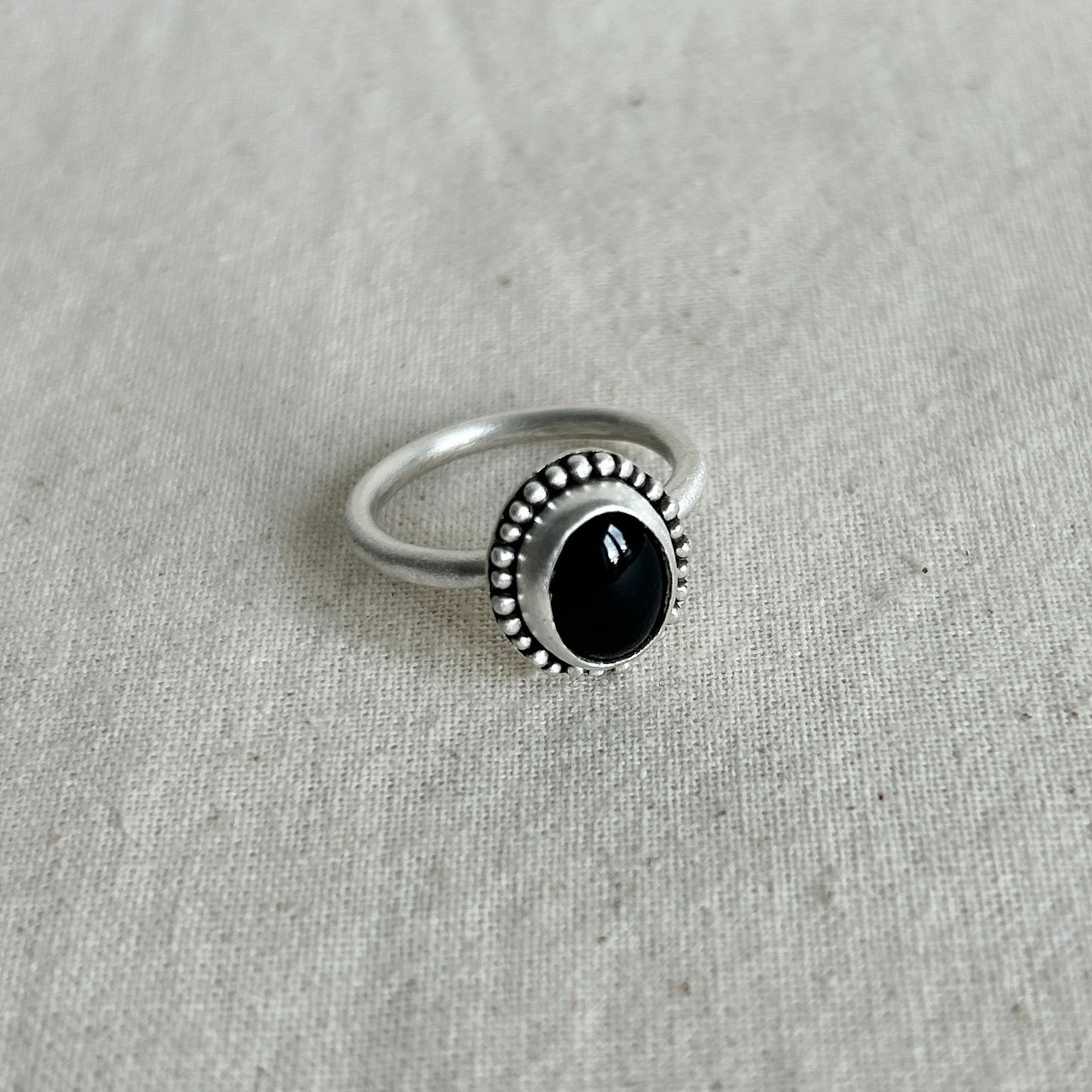 Silver ring with a black gemstone on a gray fabric background
