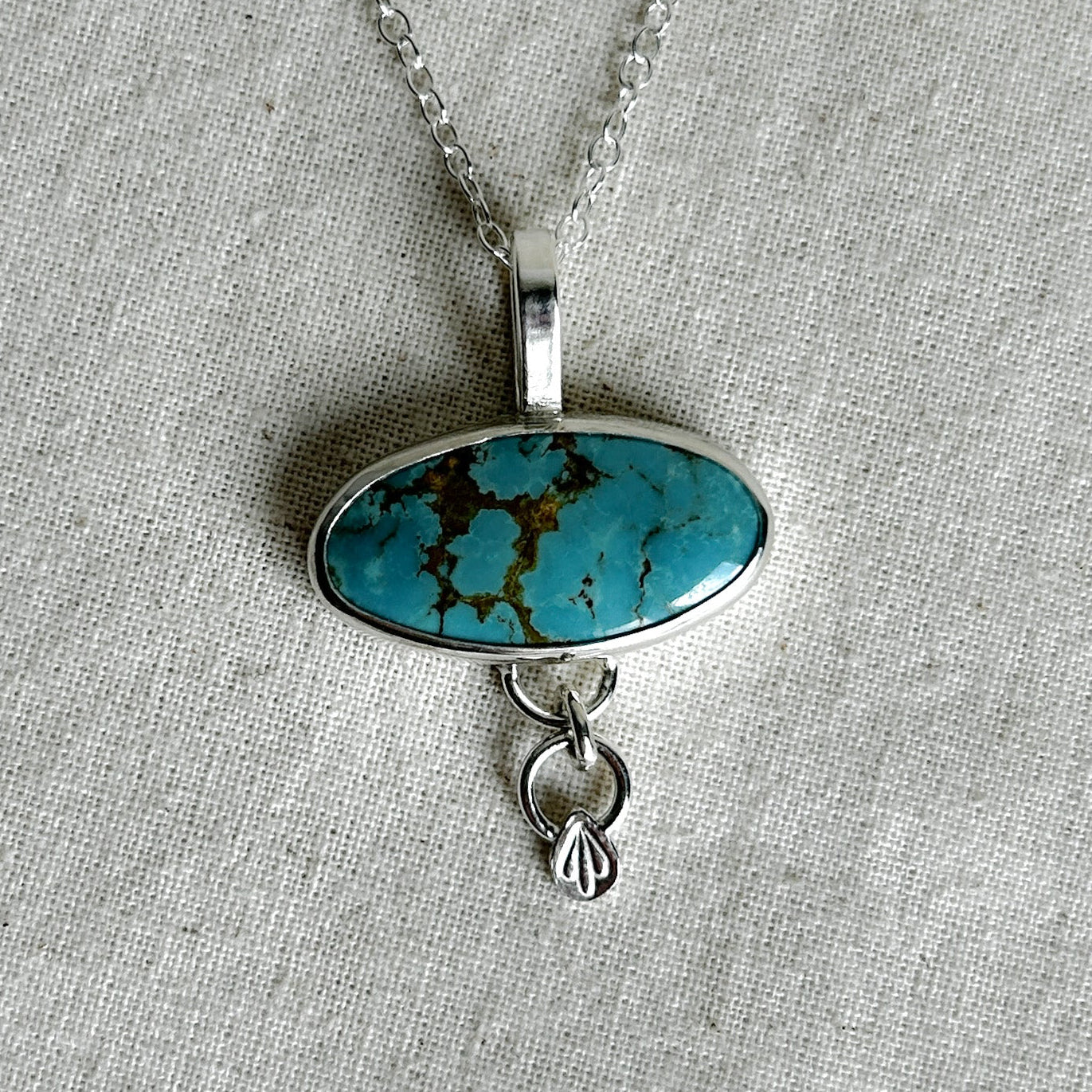 Turquoise pendant necklace on a gray fabric background