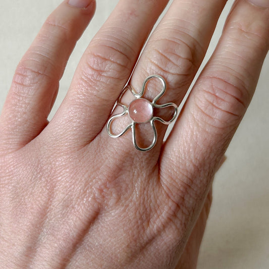 Light pink gemstone in silver flower design on a hand