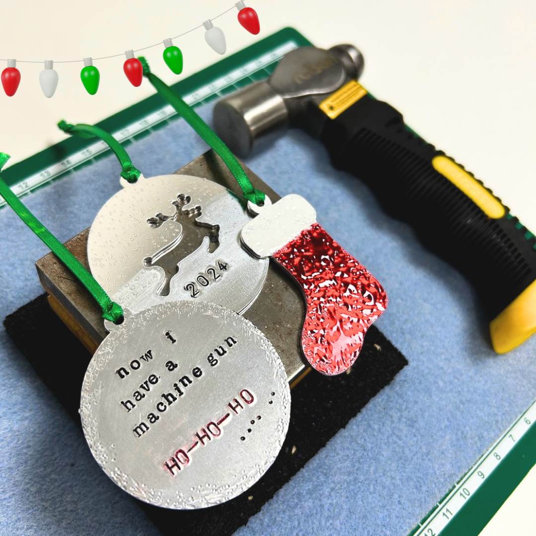 Decorative metal tags with text and a red ornament on a blue surface with a hammer.
