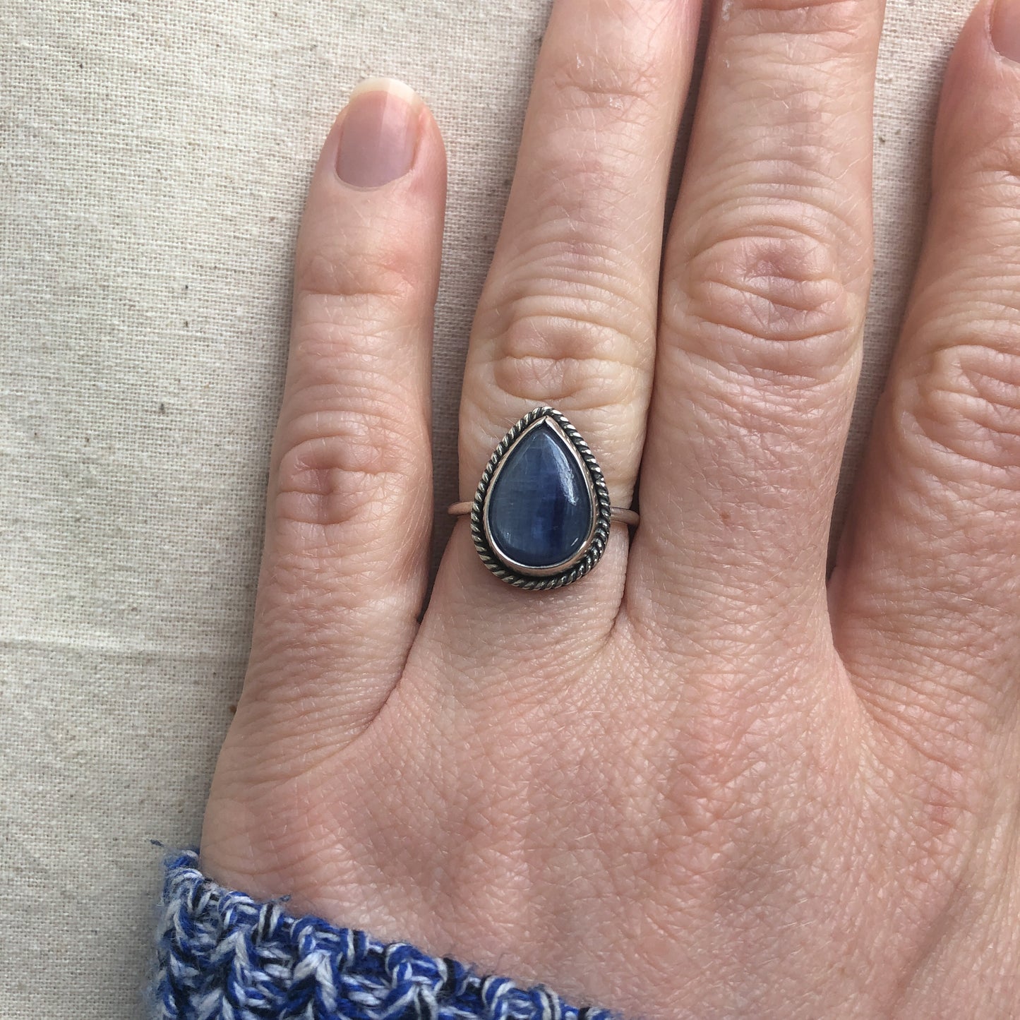 Blue kyanite gemstone ring with sterling silver band on model's hand