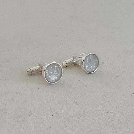 Silver cufflinks with a textured design on a light gray background