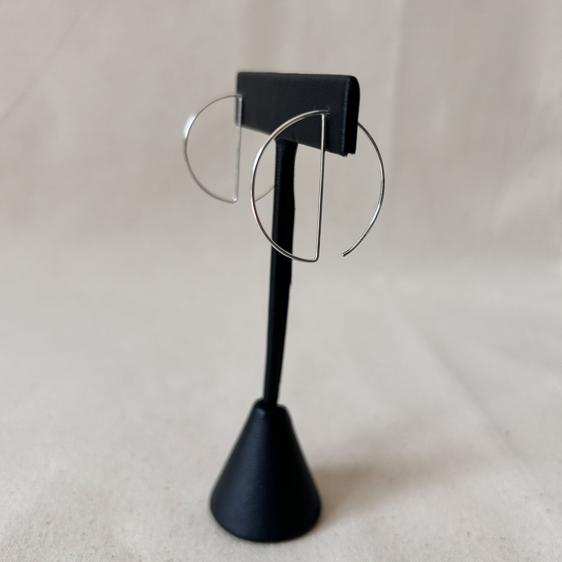 Threader hoop earrings on black display stand