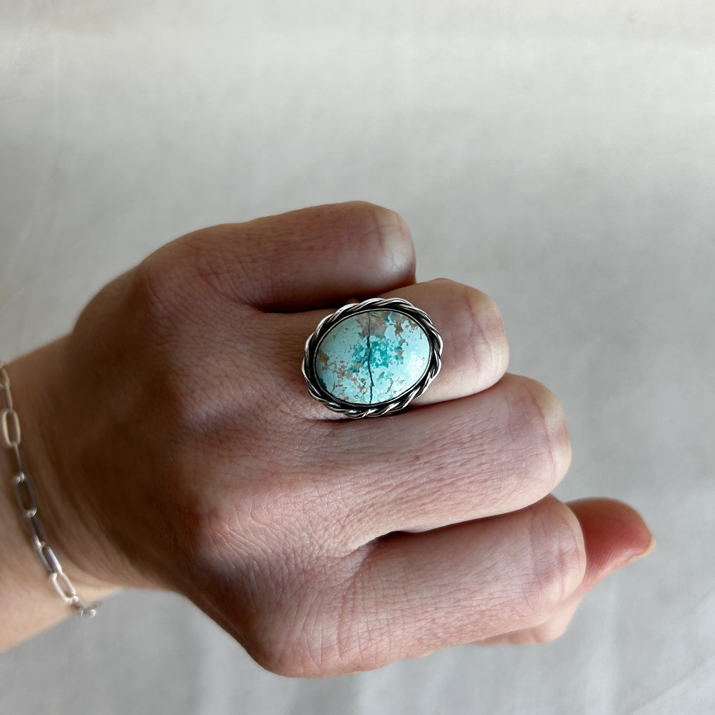 Model wearing a rope ring with oval light blue turqouise gemstone