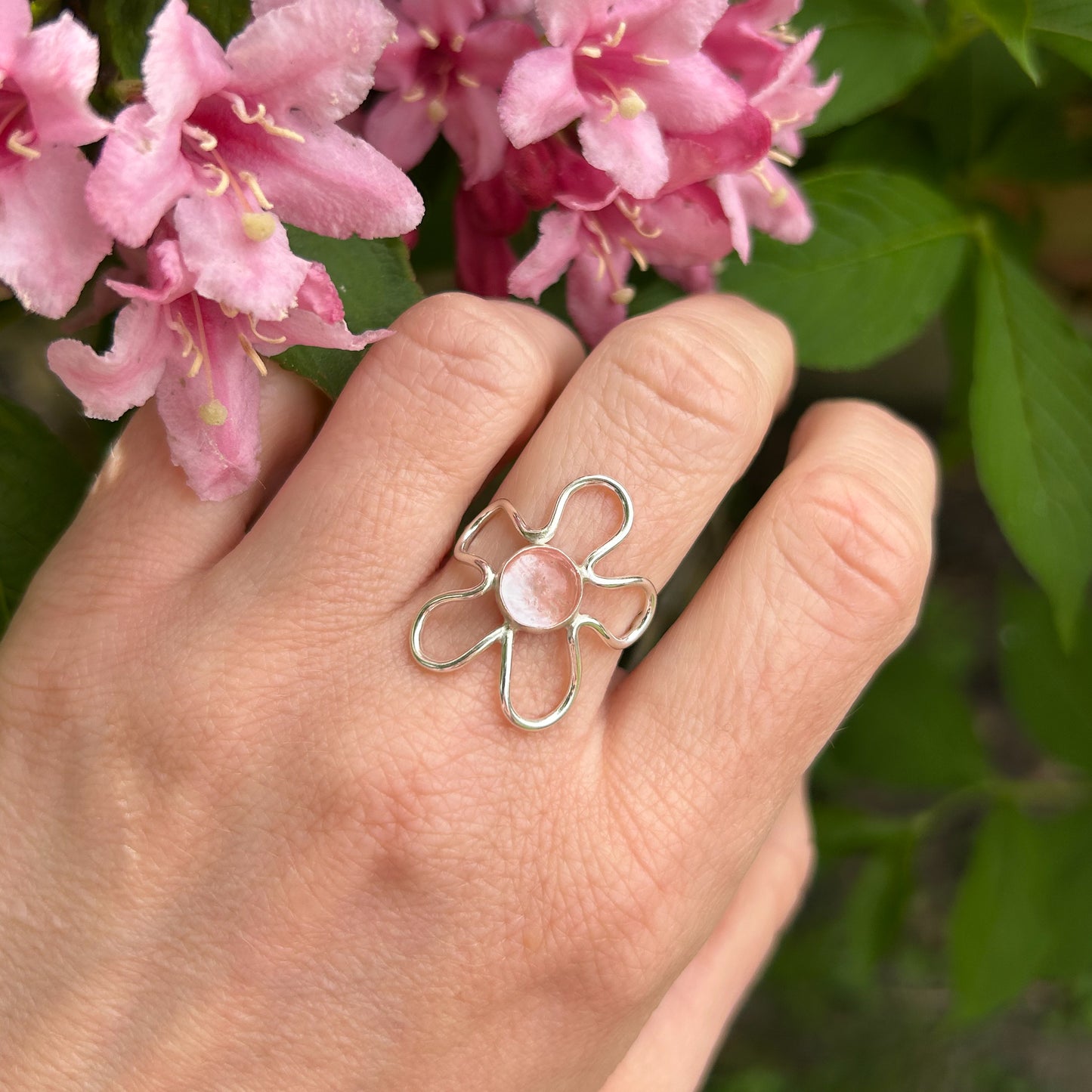 Light pink gemstone flower ring with pink flower background