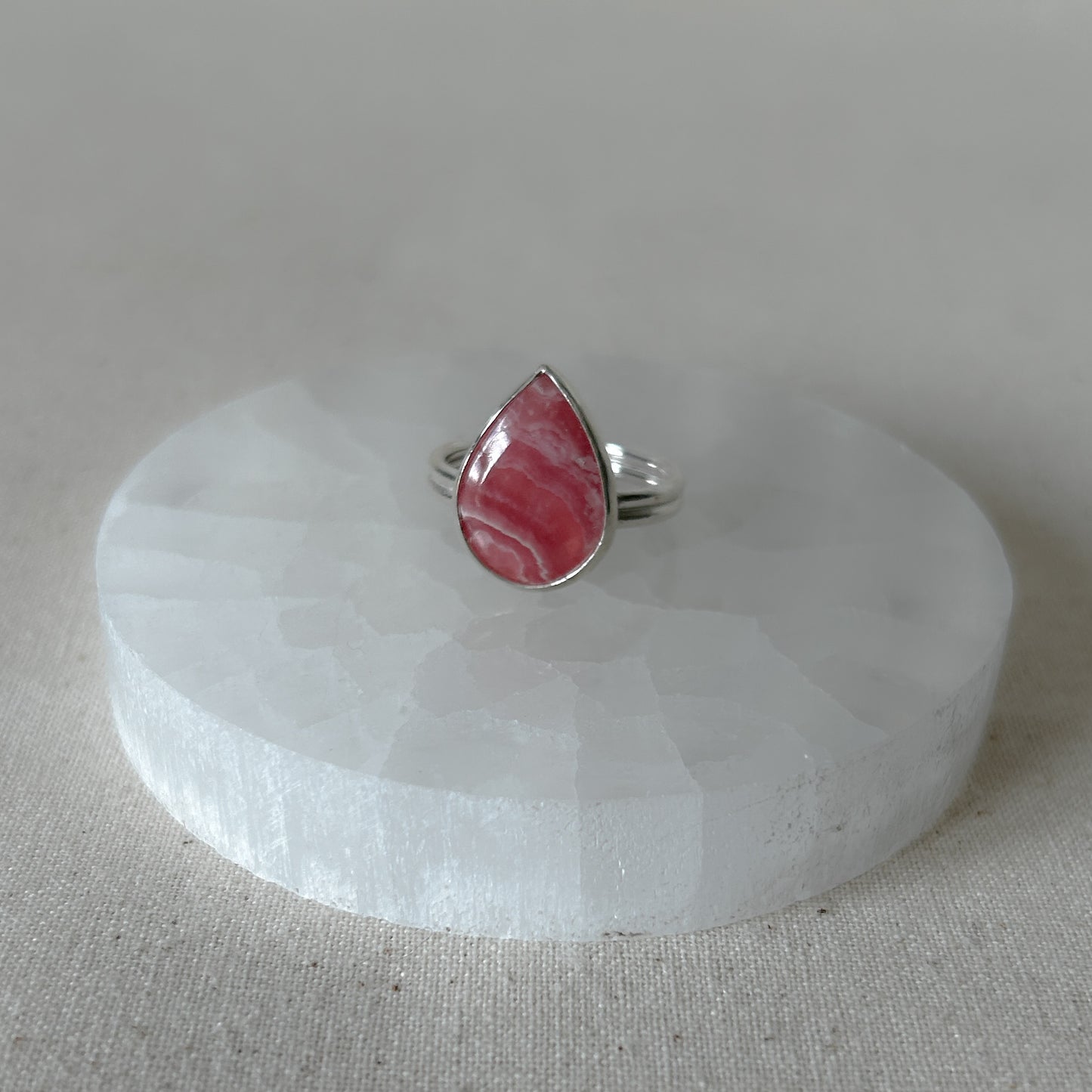 Pink and silver rhodochrosite ring on stone display