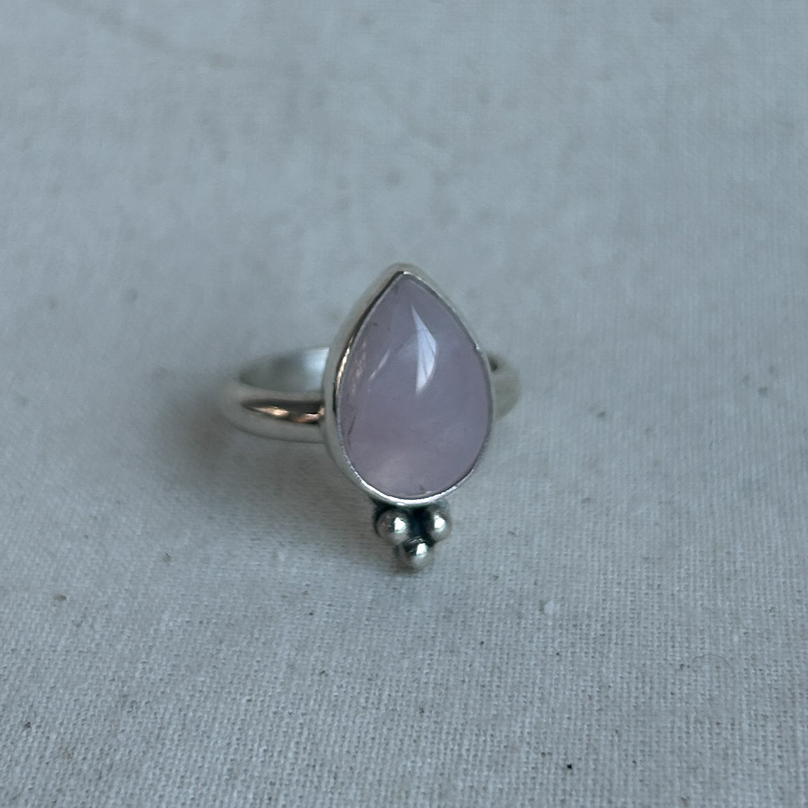 Closeup of a rose quartz silver ring on grey background