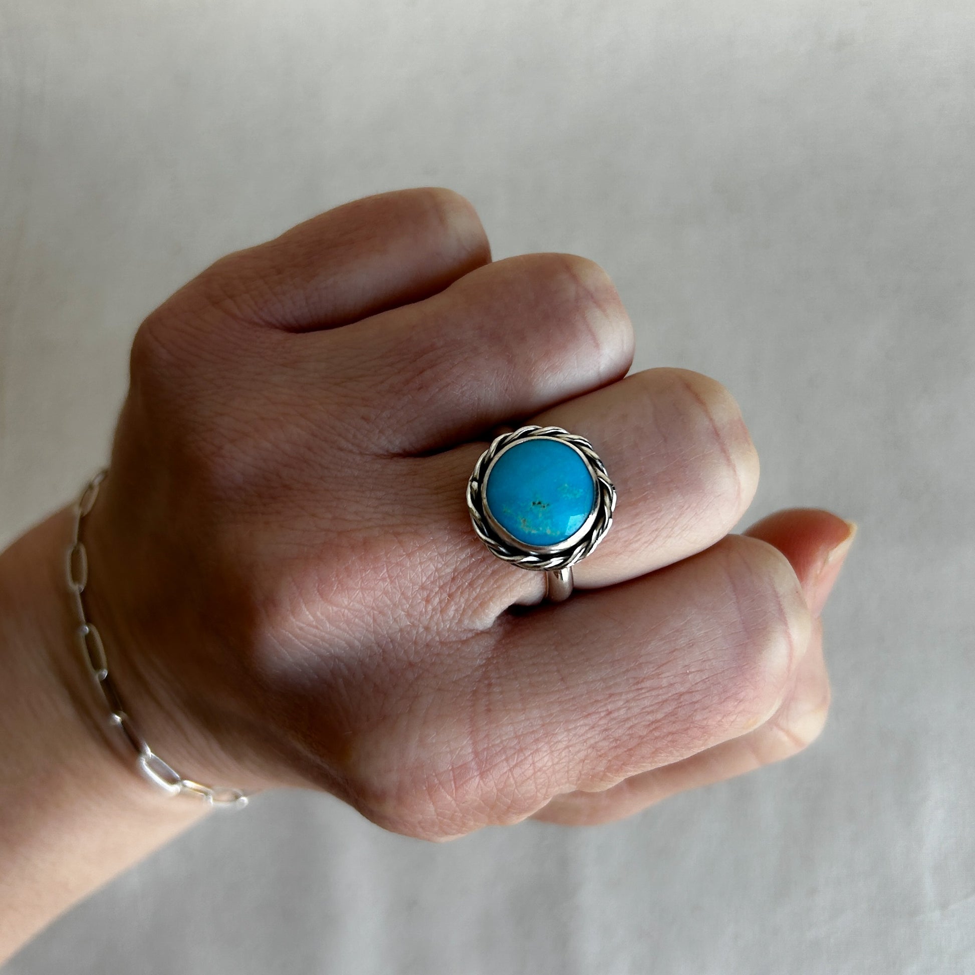 Model wearing a turquoise ring set in rope-like silver border