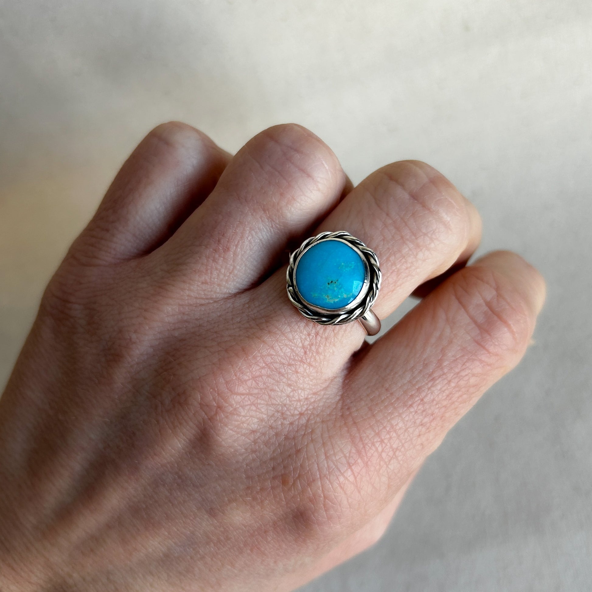 Model wearing silver statement ring with bright blue turquoise gemstone.