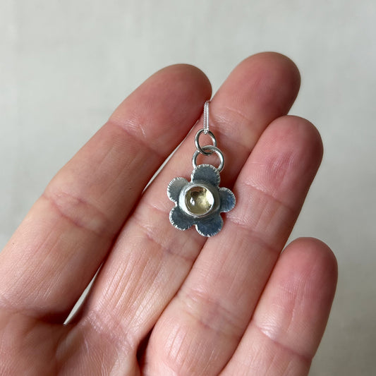 Small silver flower pendant being held in persons hand