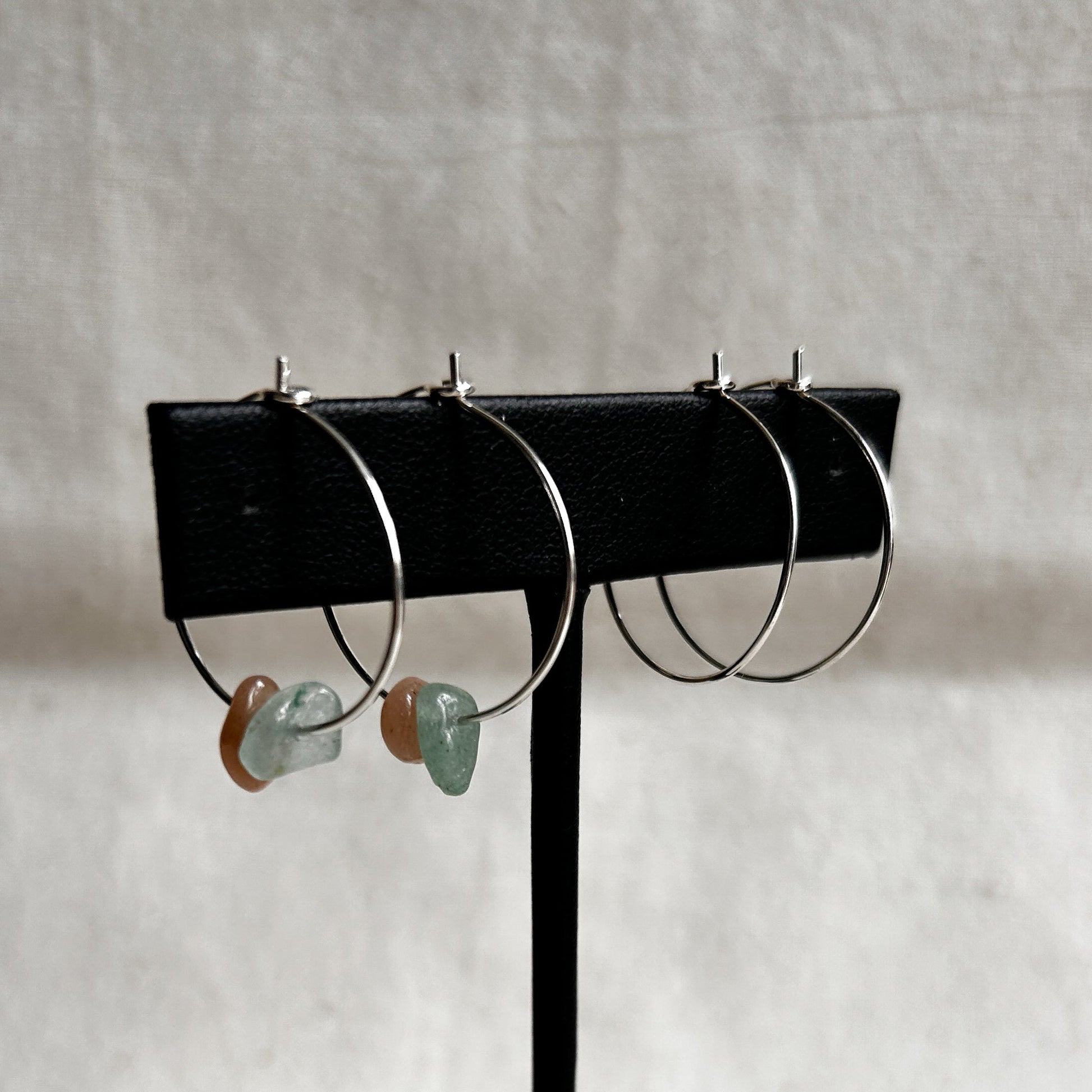 Set of hoop earrings on a black stand against a light gray background