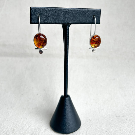 Baltic amber dangle earrings on black leather stand