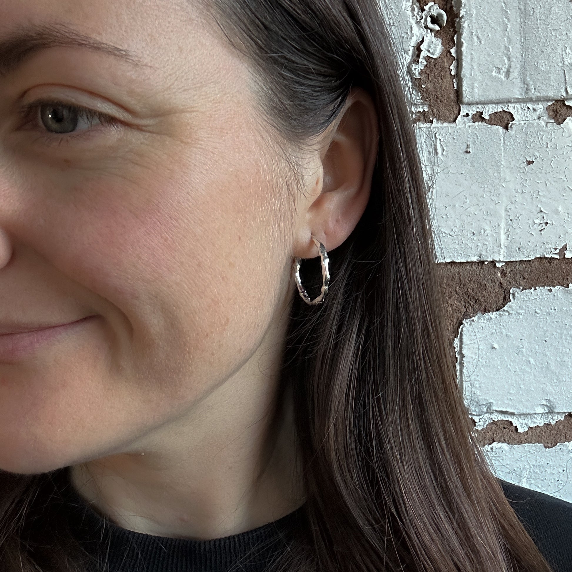Model wearing a pair of silver medium hoop earrings