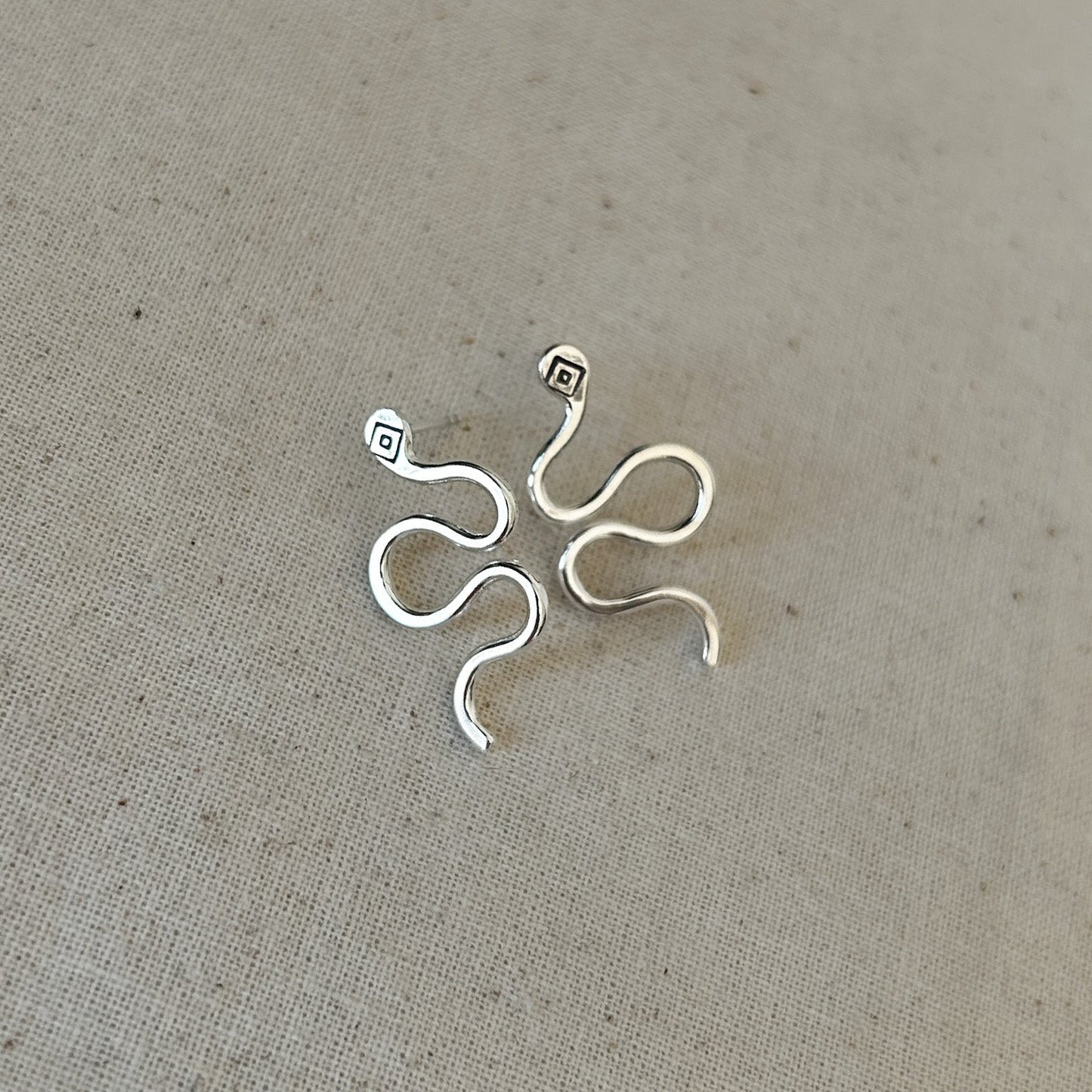 High-polish silver stud earrings shaped like snakes