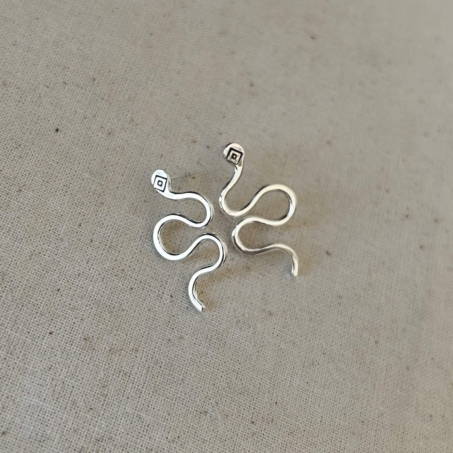 High-polish silver stud earrings shaped like snakes