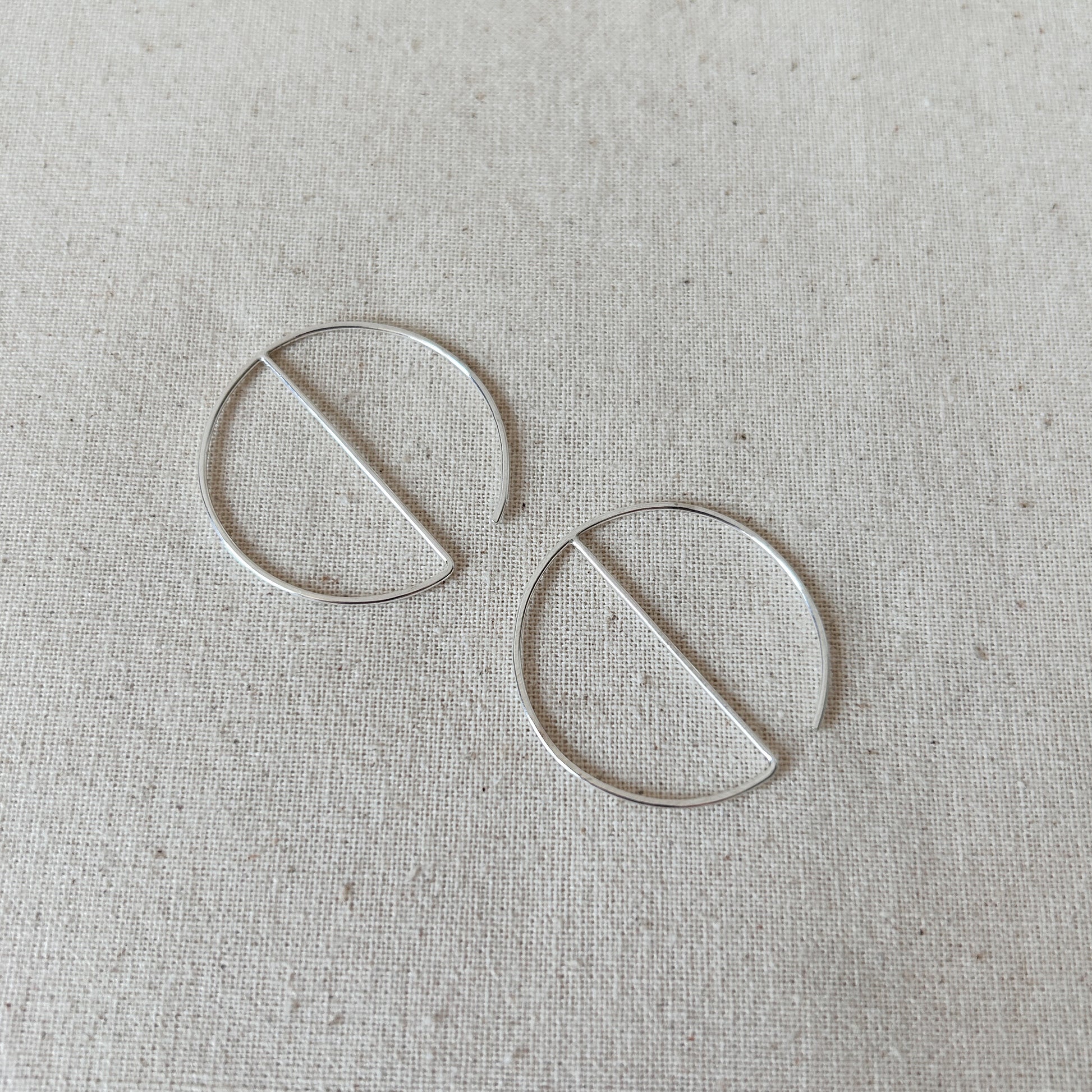 Small silver threader hoop earrings on grey fabric