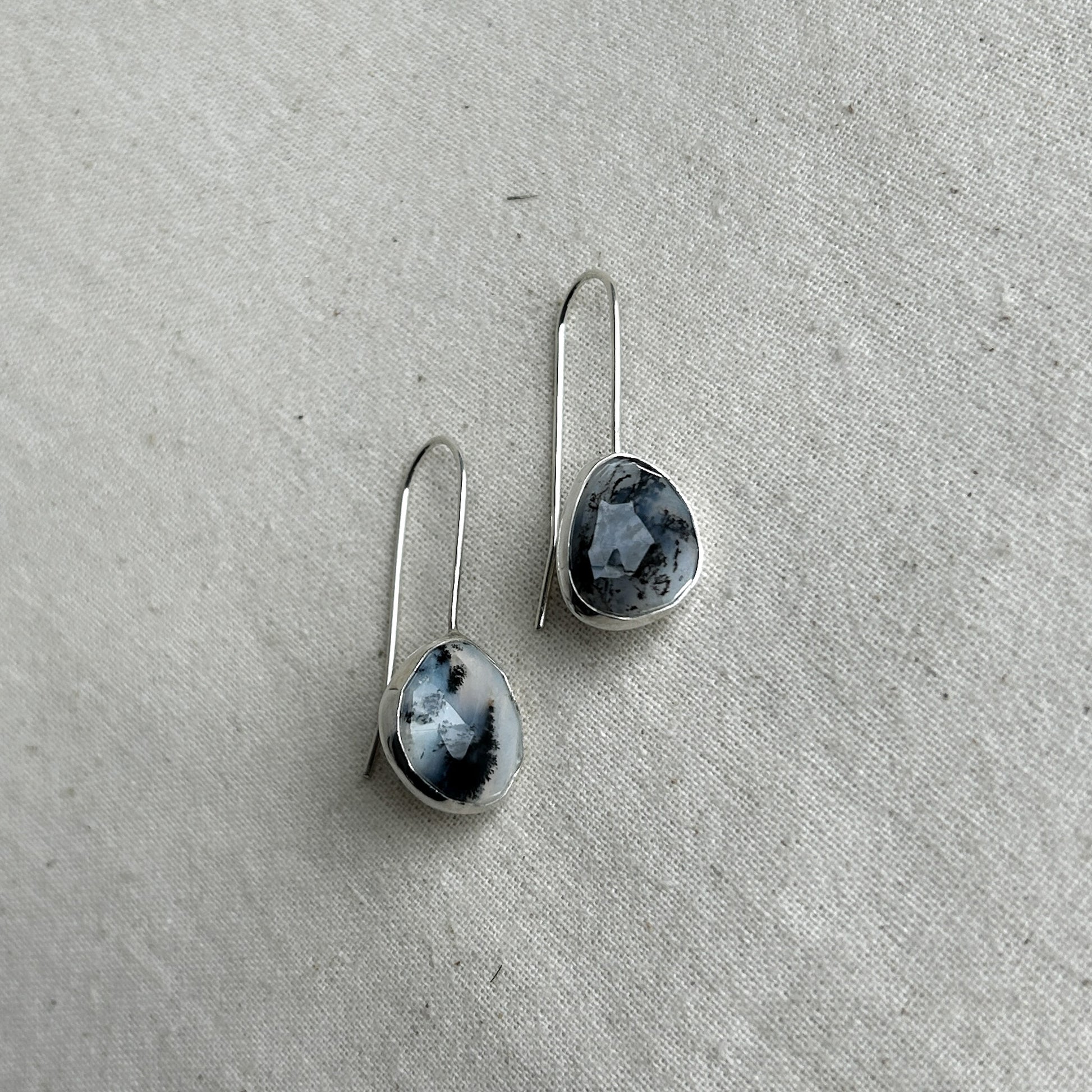 Silver dangle earrings featuring black and white opals