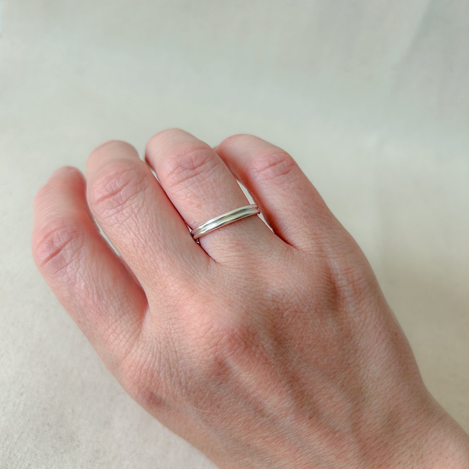 Double-band silver stacking ring on model's hand