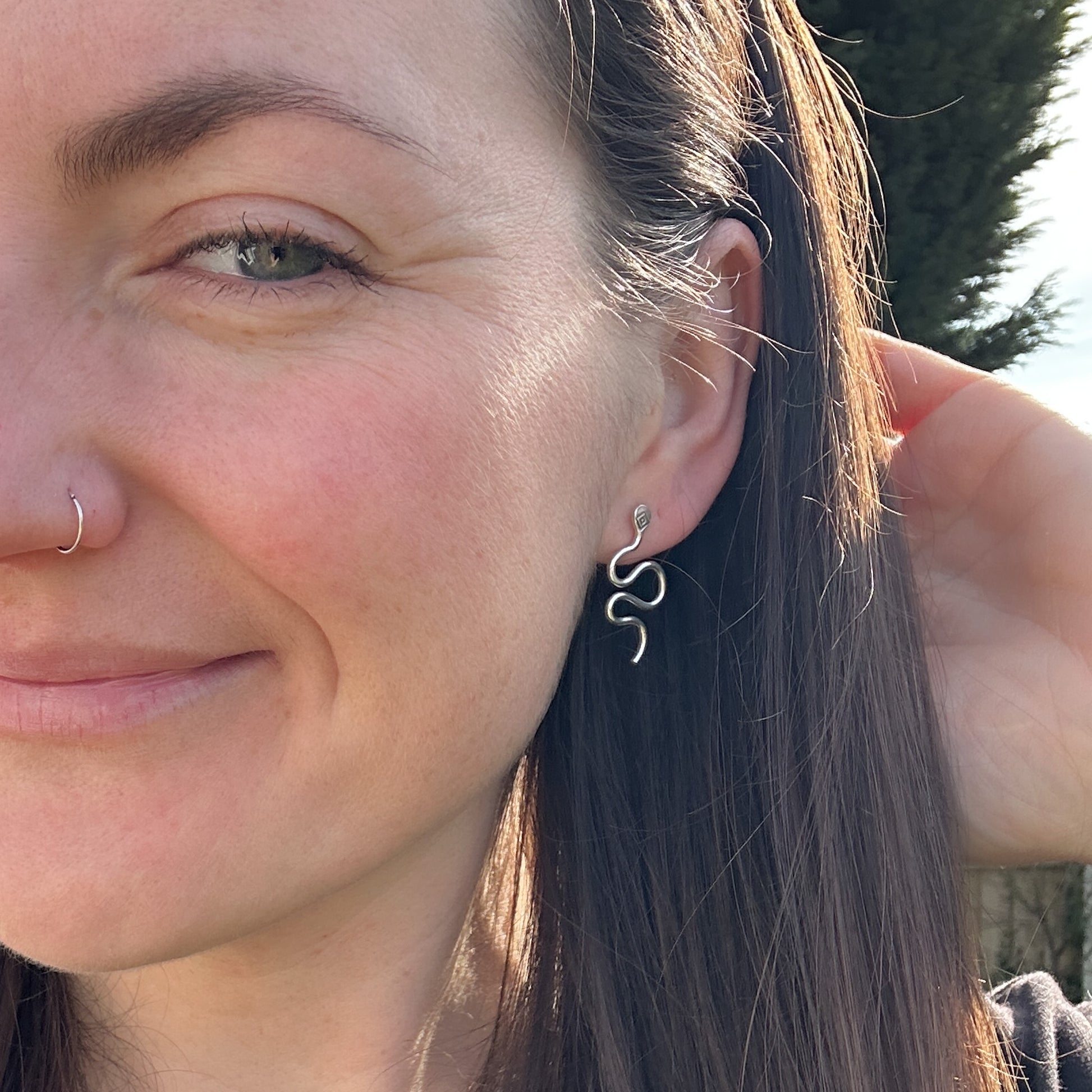 Model wearing silver snake earrings