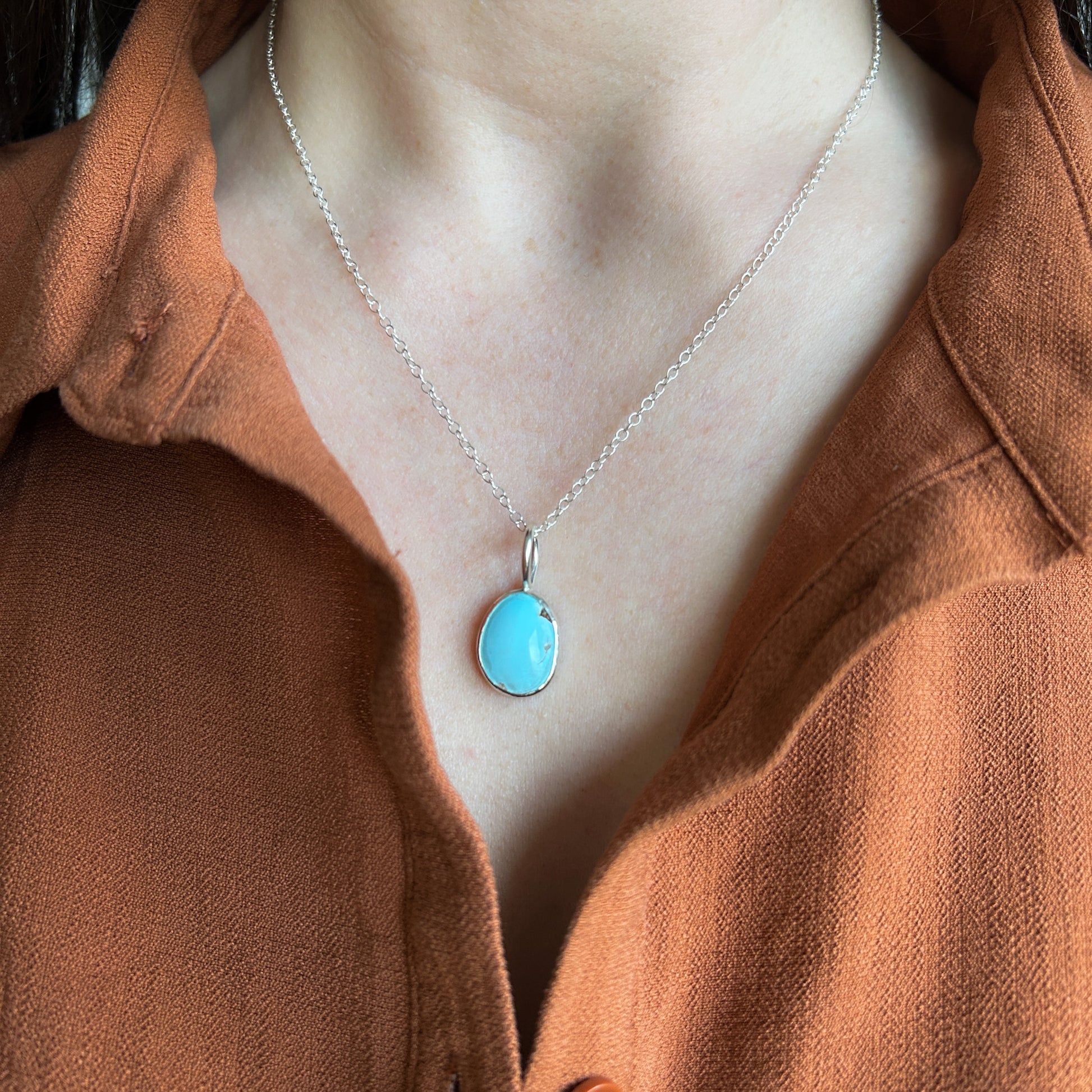 Small turquoise silver pendant hanging on sterling silver chain