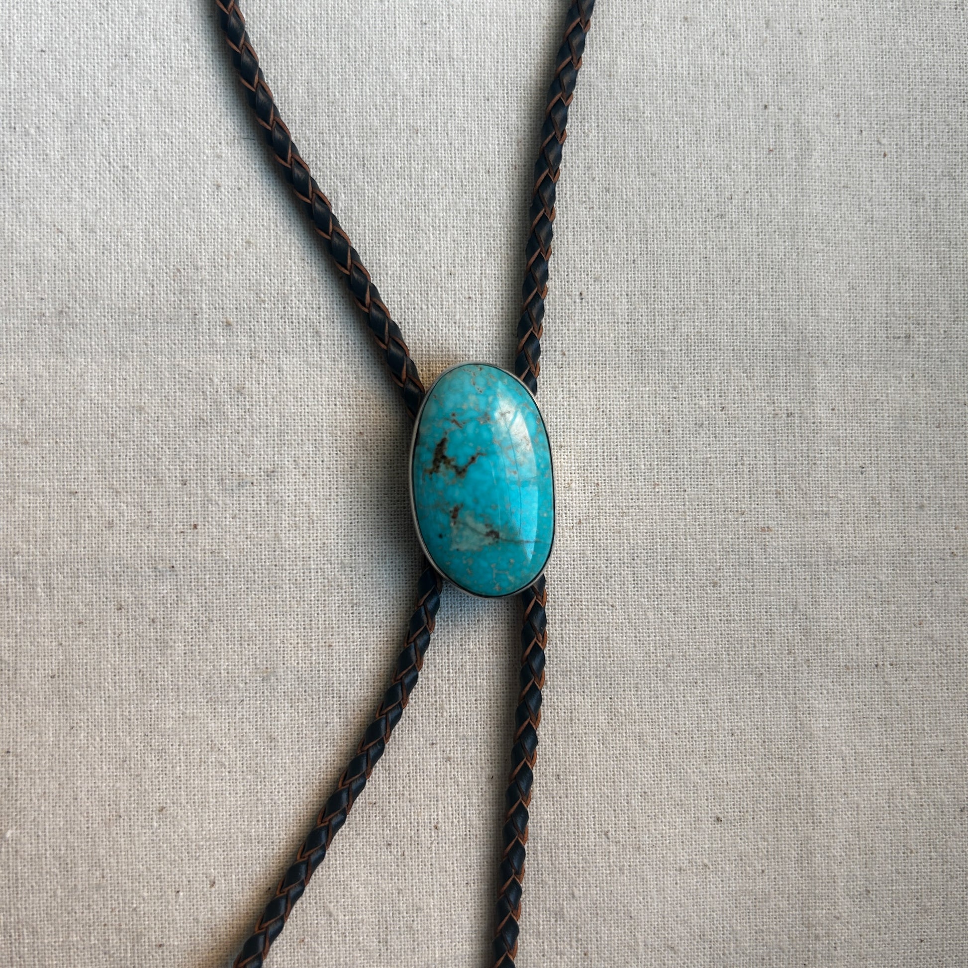 Freeform turquoise gemstone set in Argentium hanging on a leather cord necklace