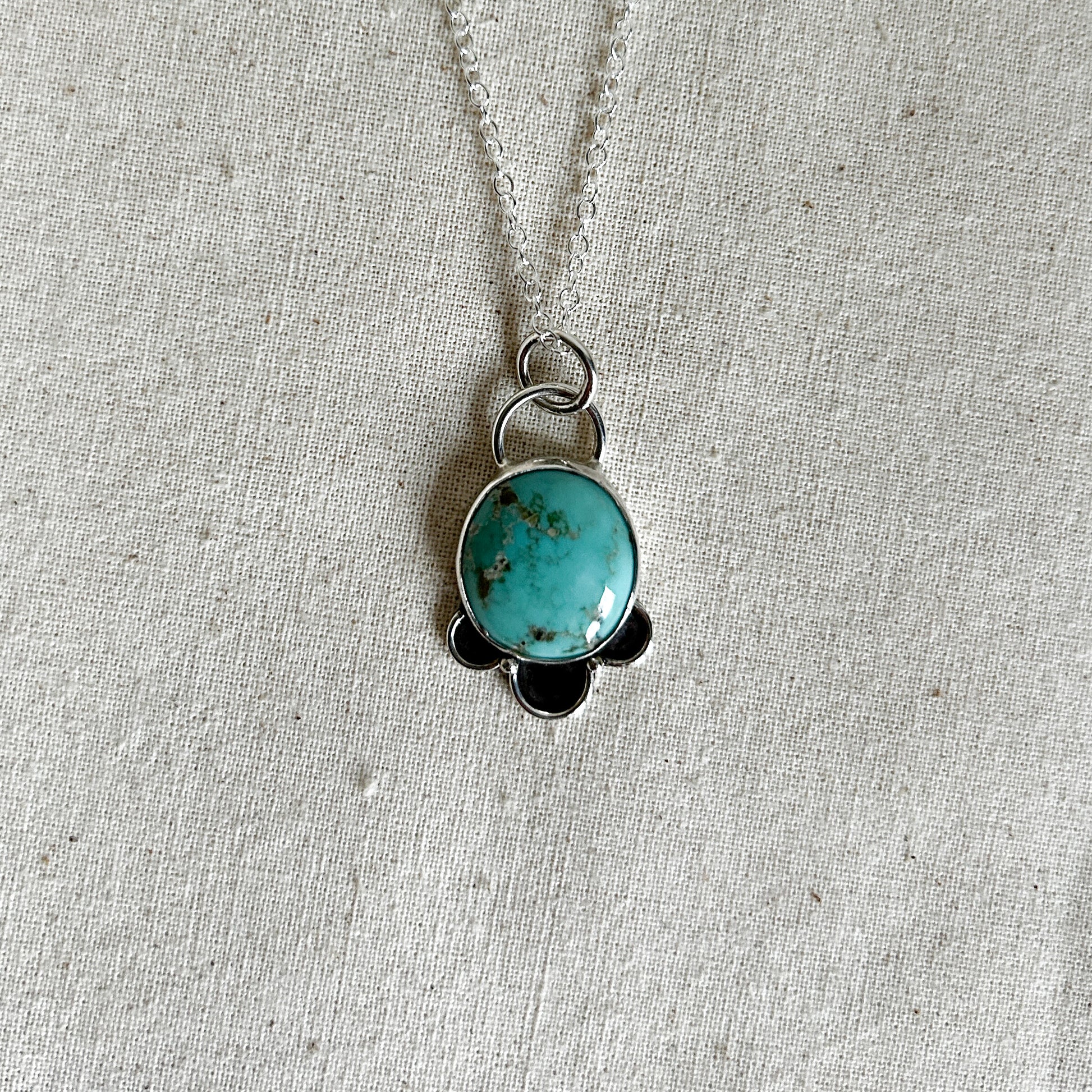 Round turquoise stone with 3 petal-like embellishments on a silver chain