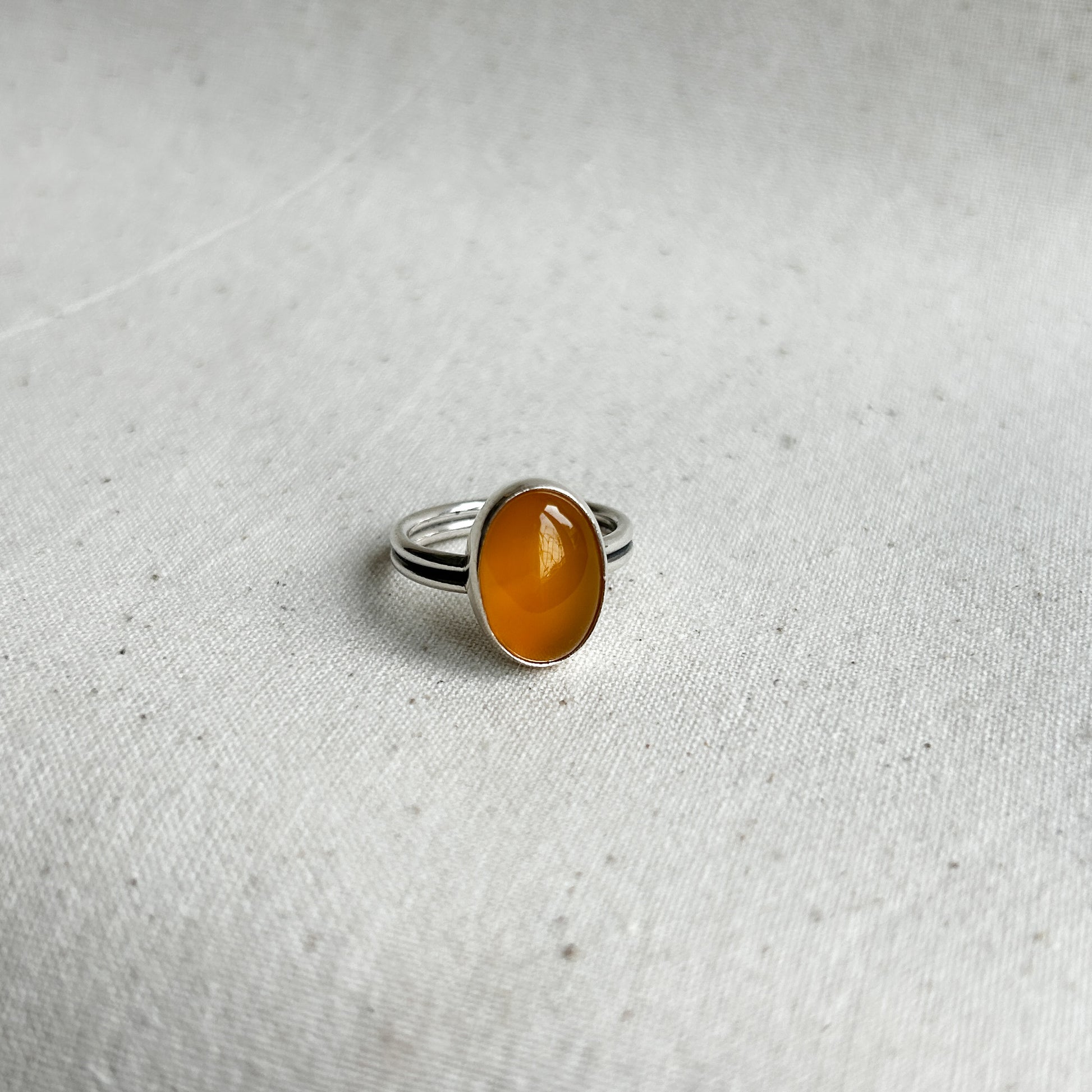A yellow chalcedony ring with a simple silver setting on a textured white background.
