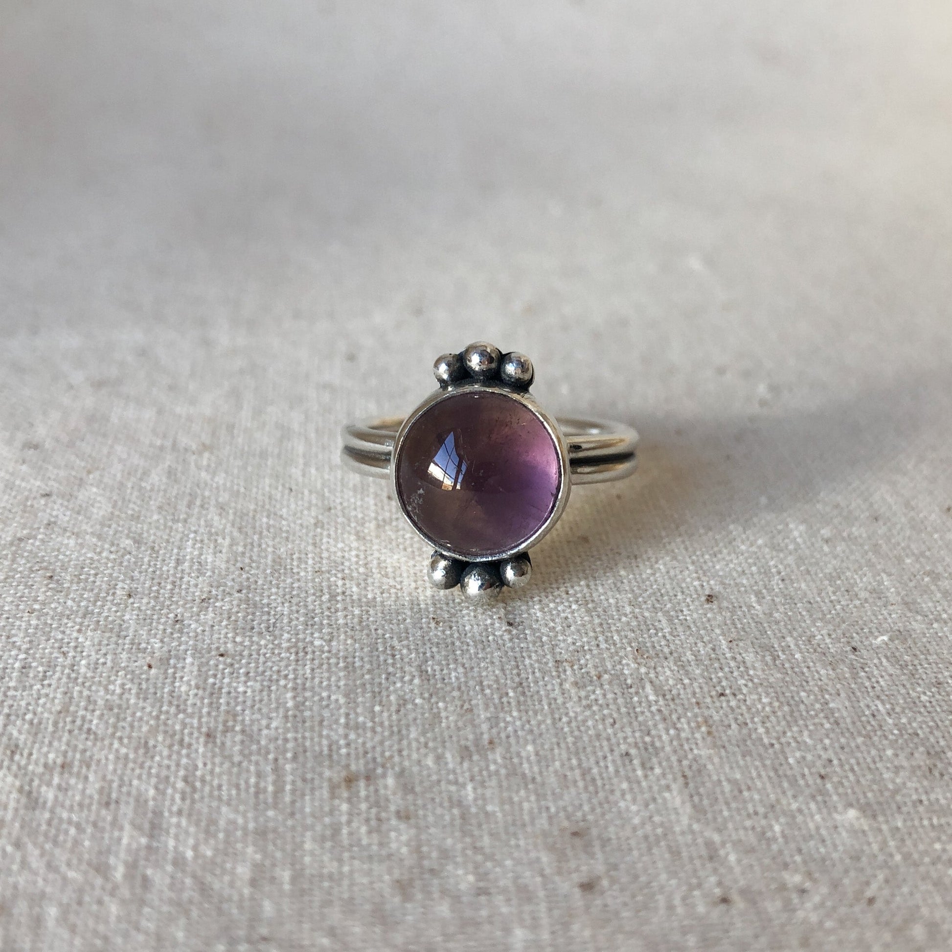 Amethyst ring with three silver orbs on each side