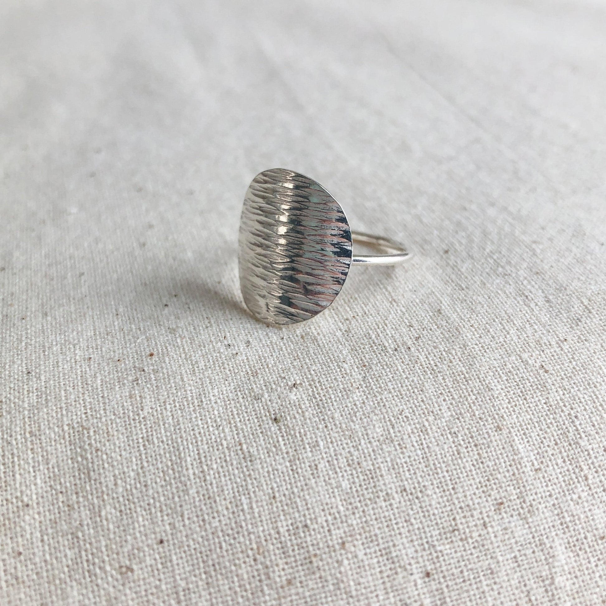 Simple silver disc ring on grey background