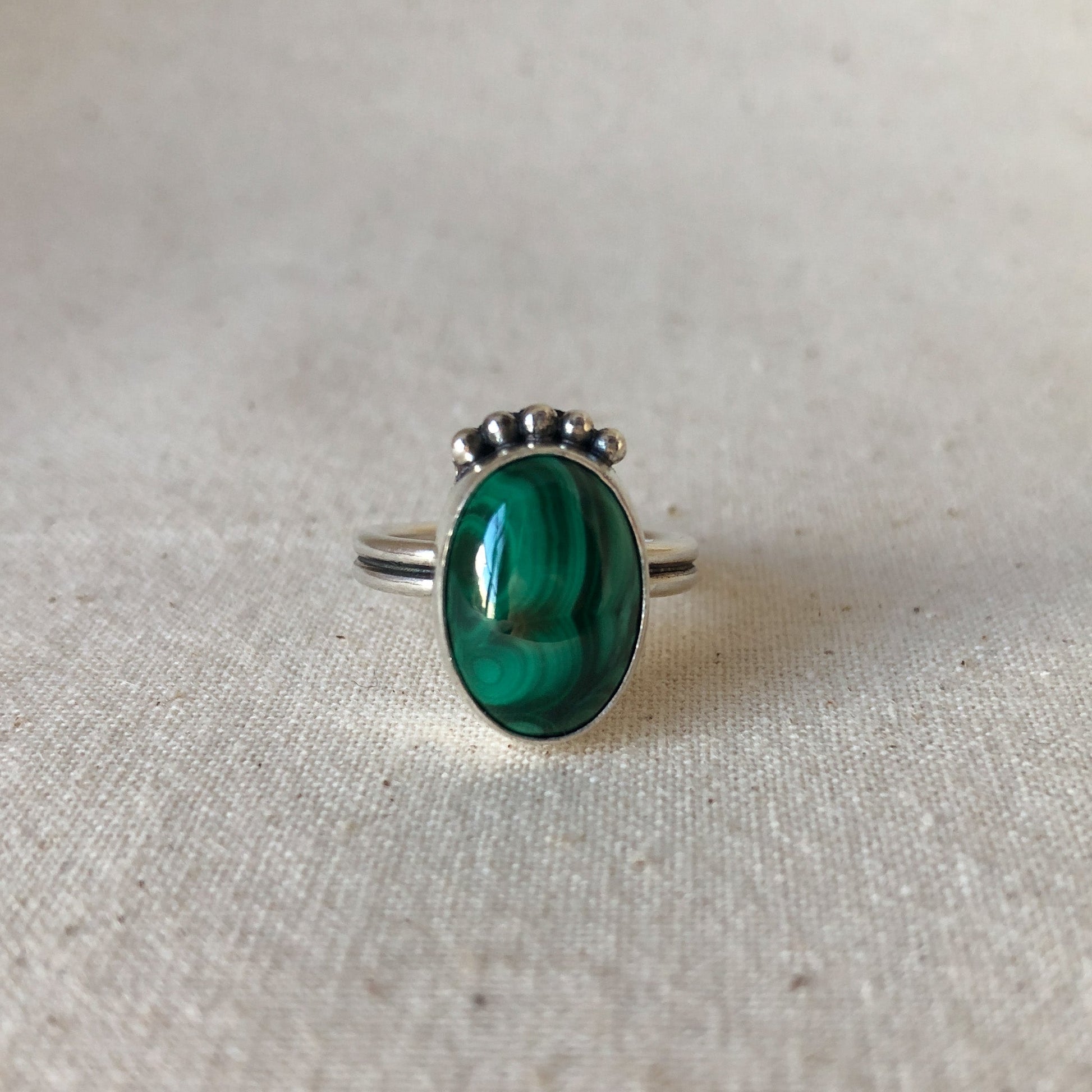 Green malachite ring with silver band  on grey background