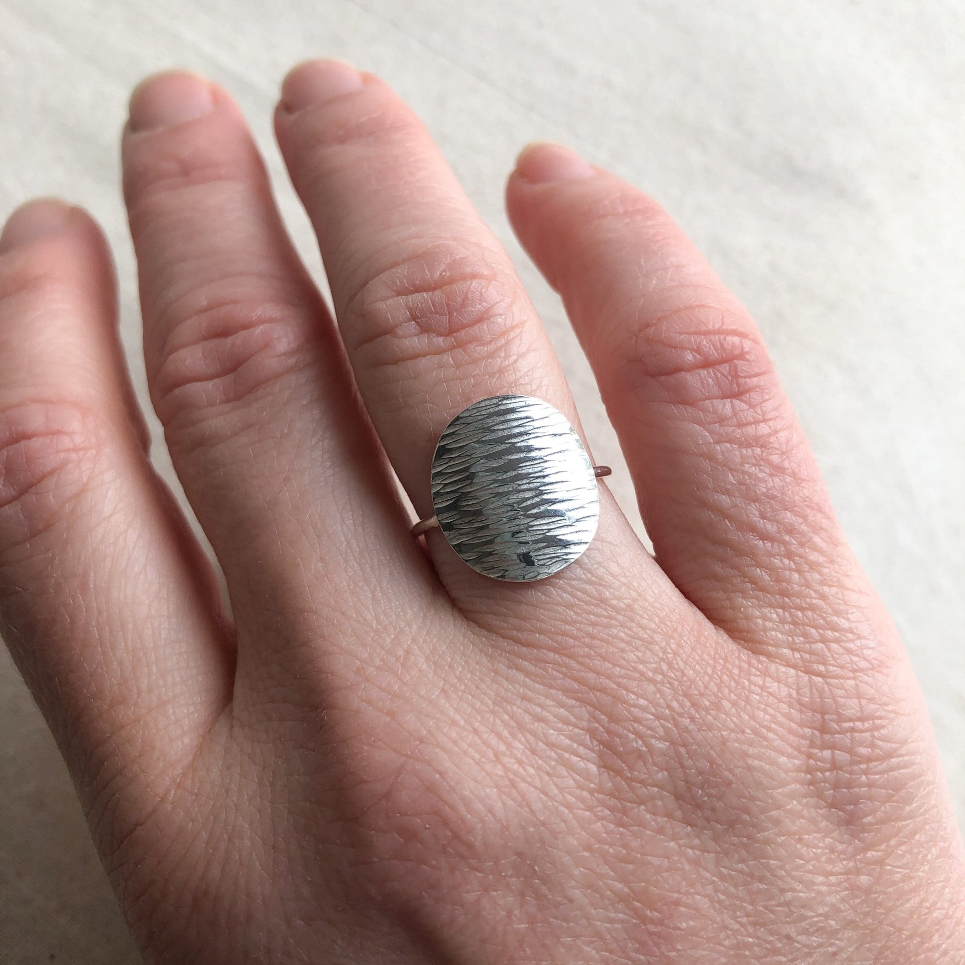 Minimal silver disc ring on model's hand
