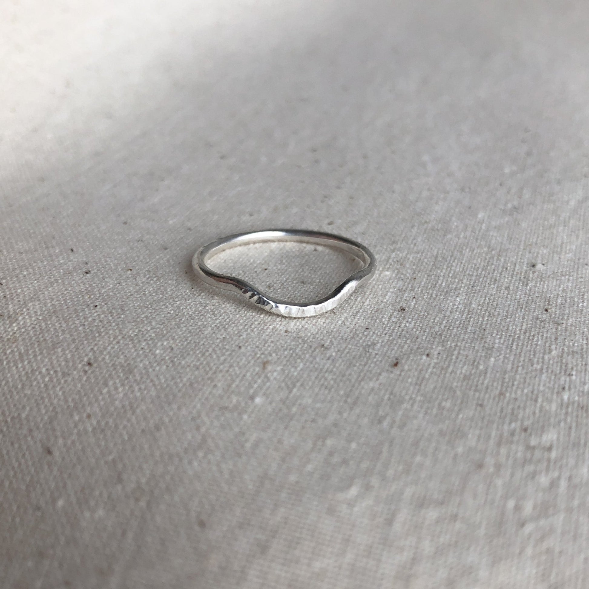 Curved stacking ring made of sterling silver on grey background