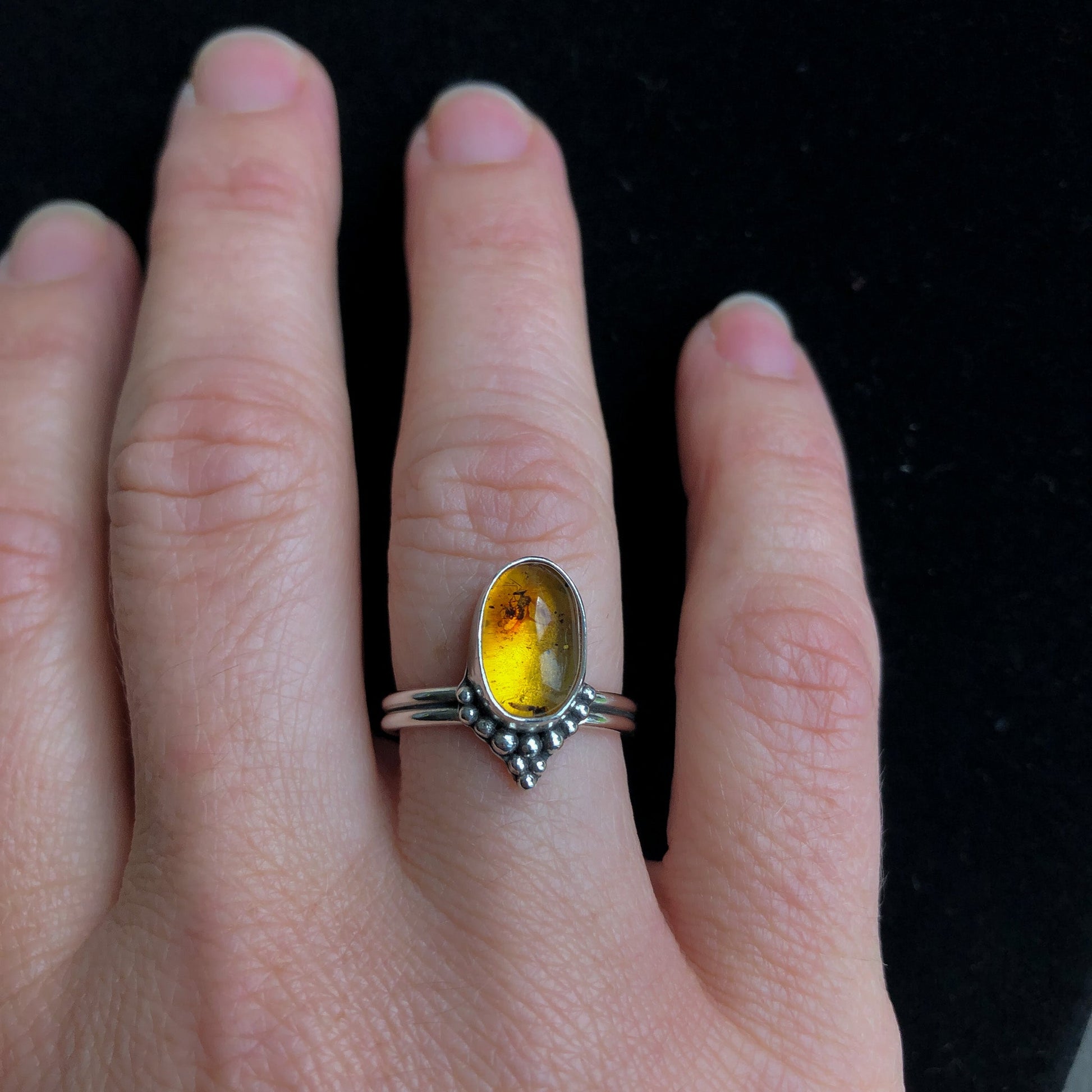 Silver amber ring with yellow gemstone on model's hand