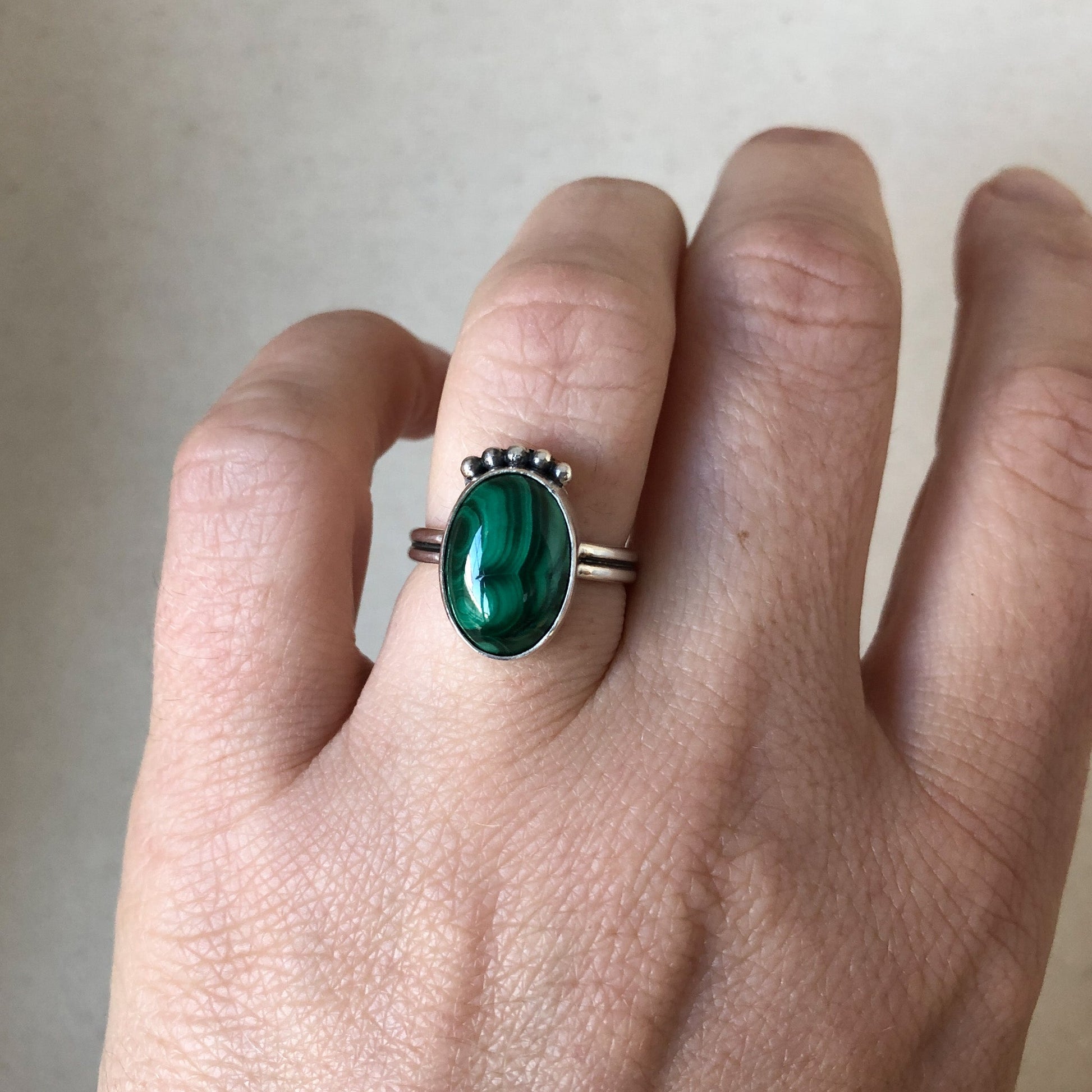 Silver malachite ring with green gemstone on model's hand