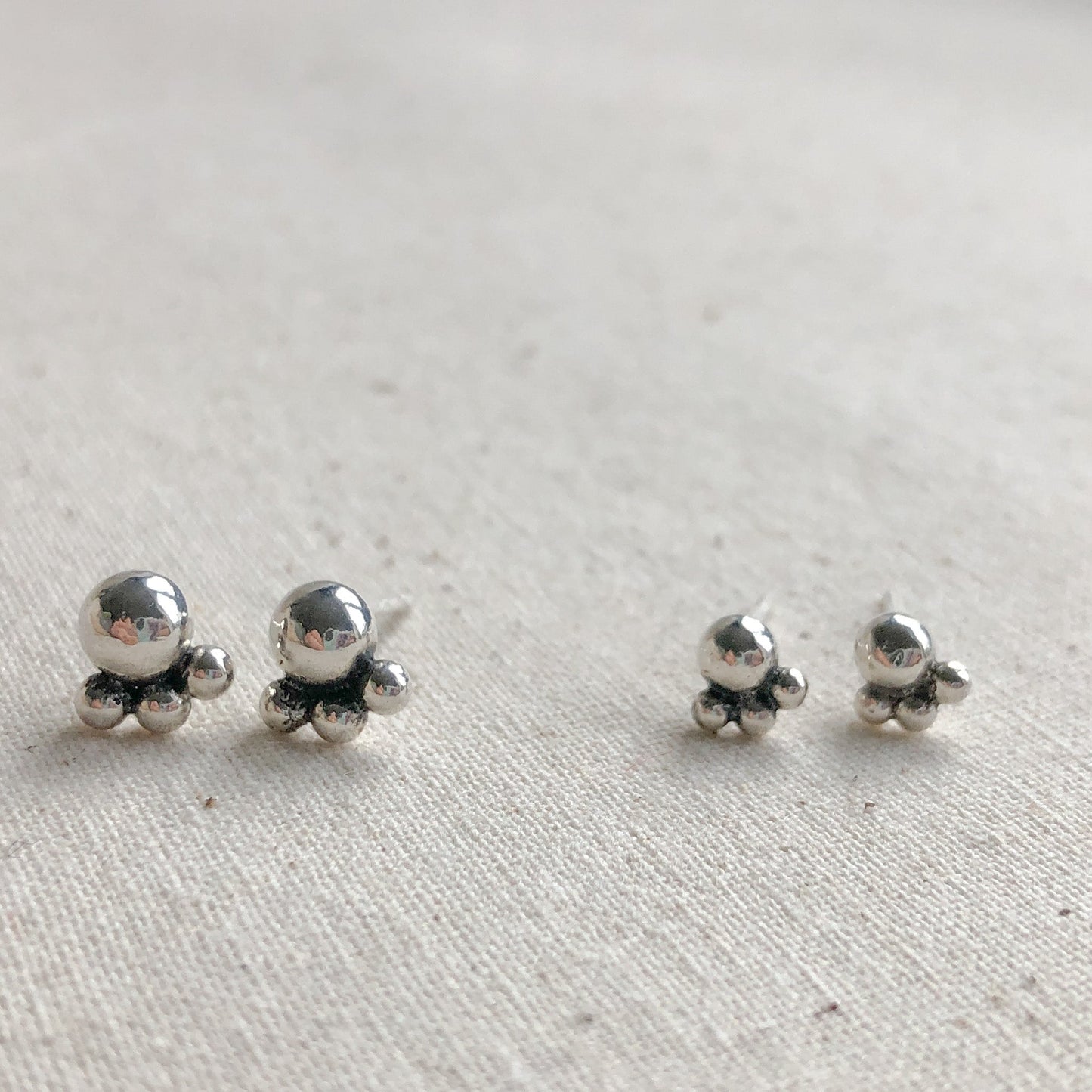 Two pairs of silver studs on a grey background