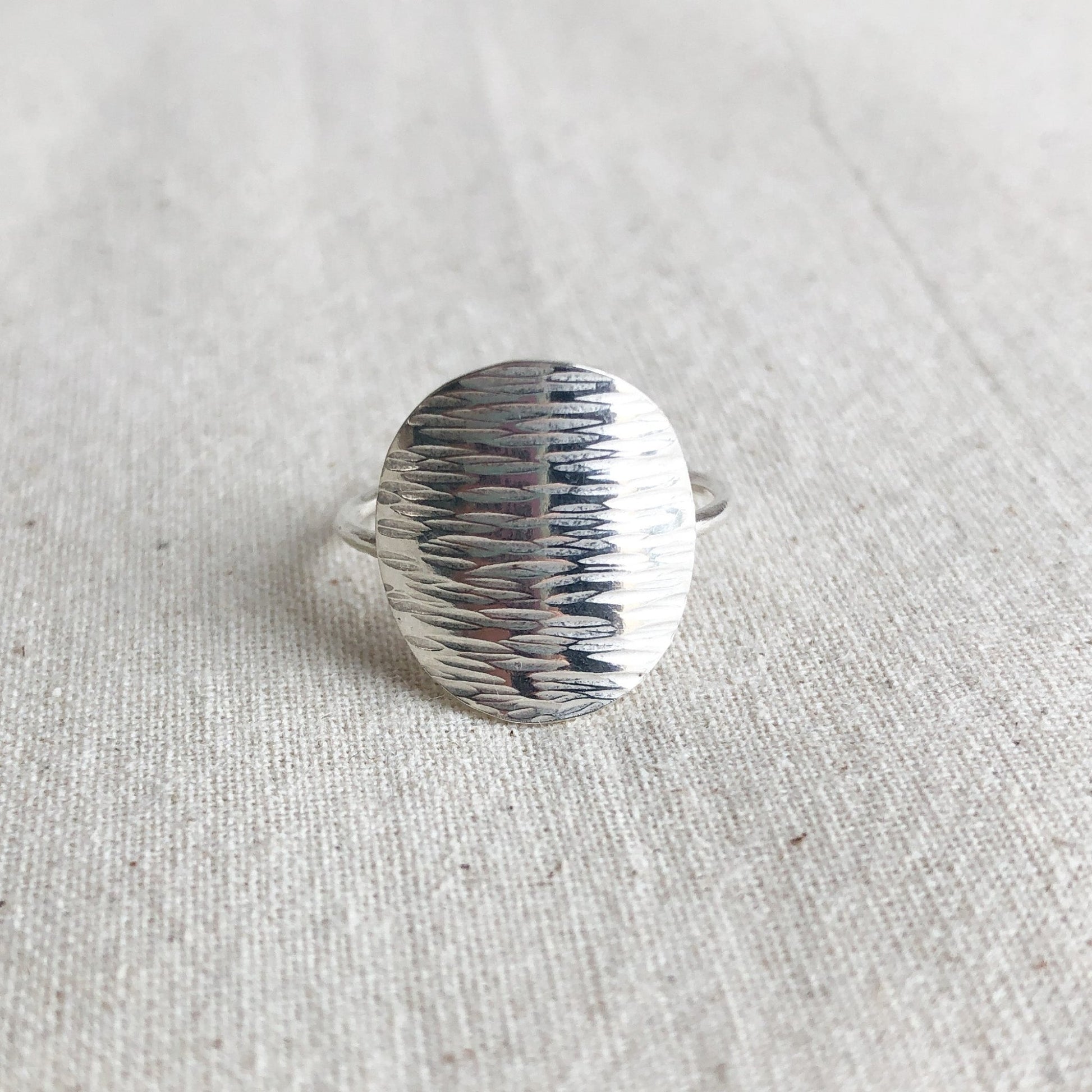 Shimmer sterling silver disc ring on grey background