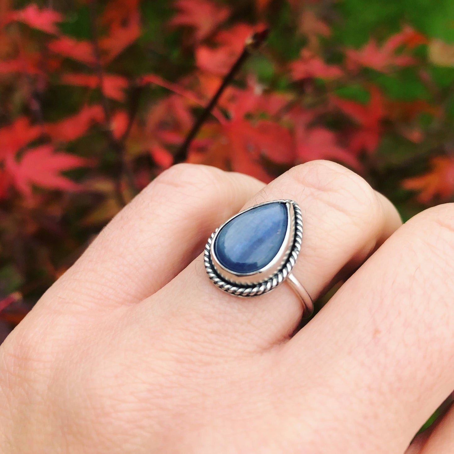 Silver ring with dark blue kyanite gemstone on model's hand