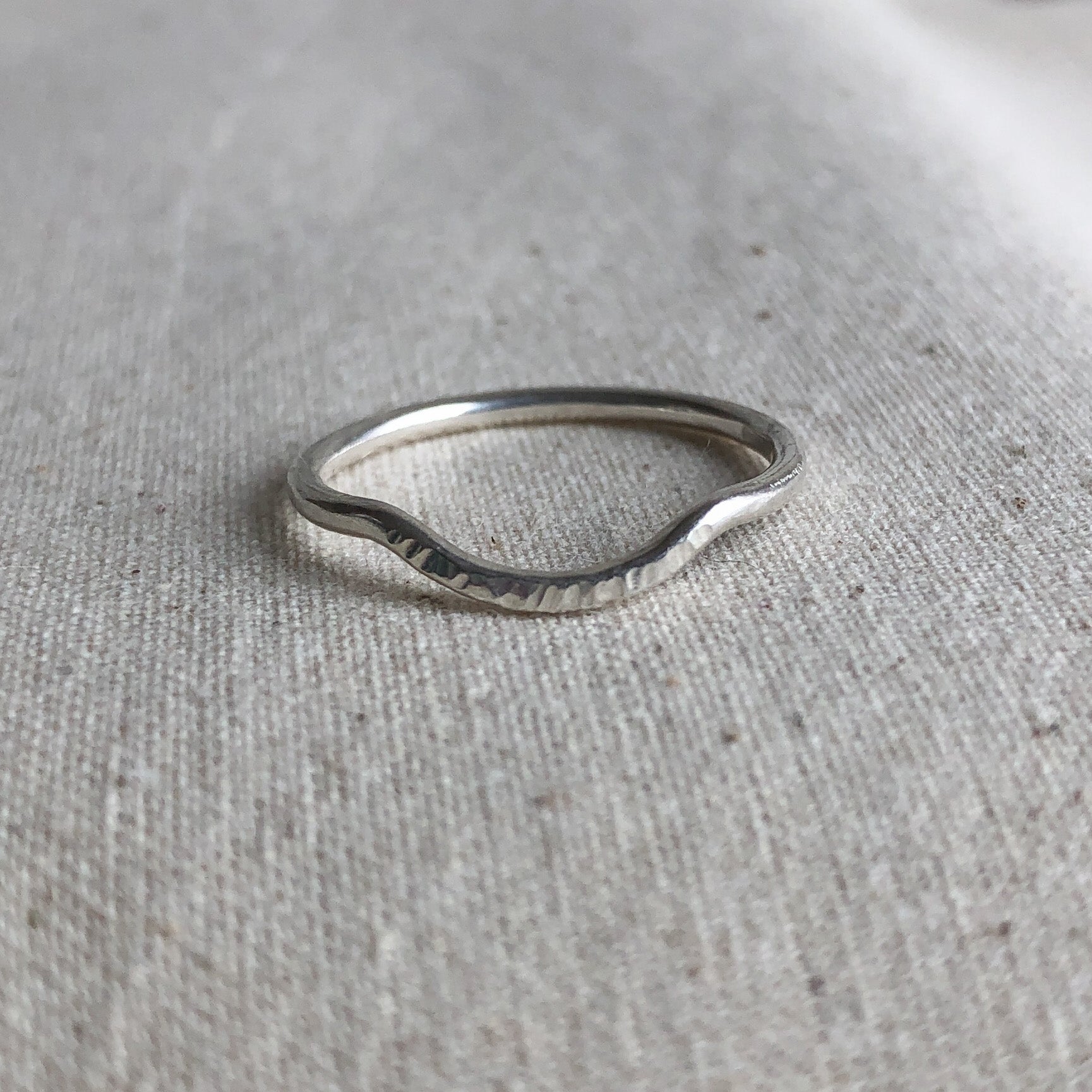 Sterling silver curved stacking ring on grey background