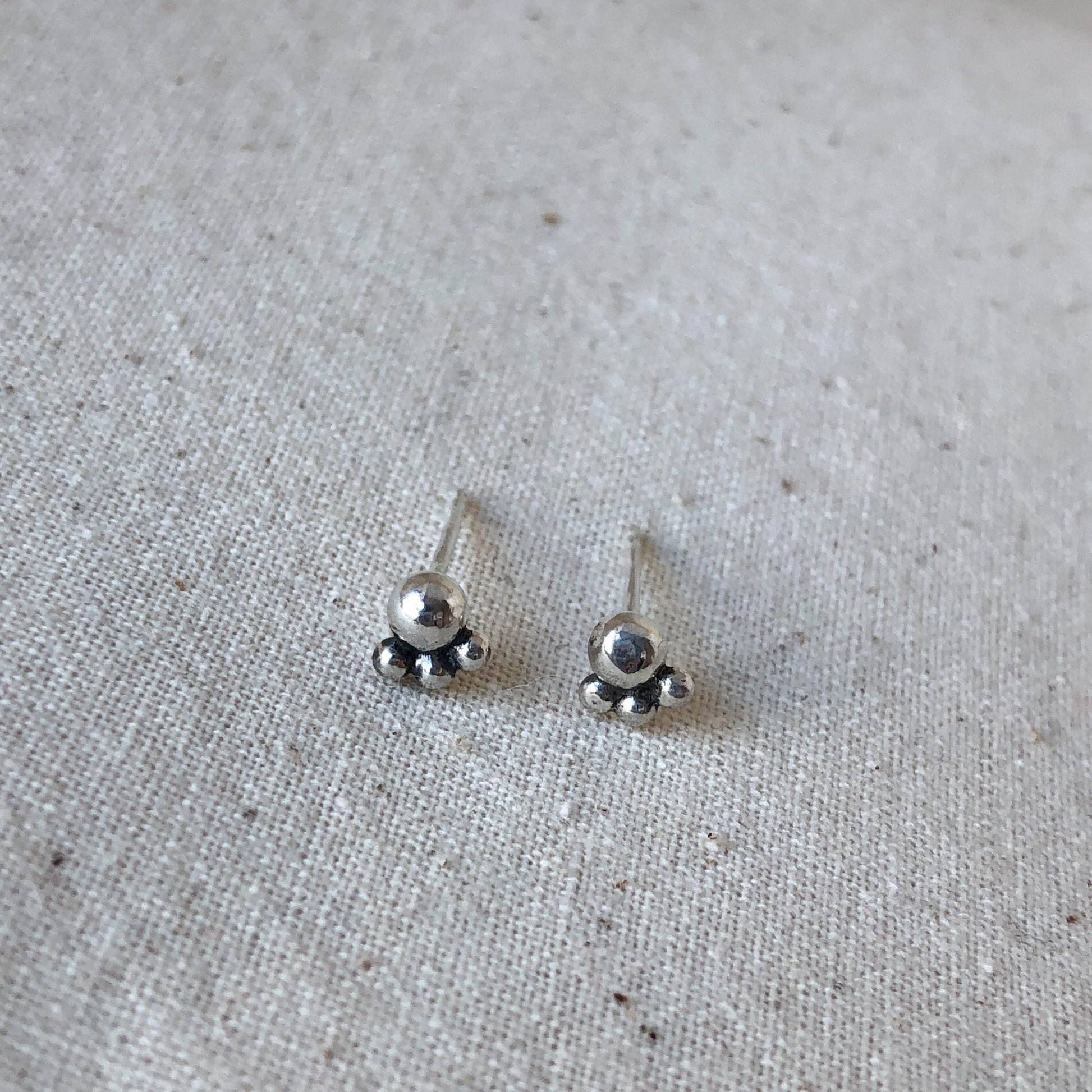 Silver ball stud earrings on grey background
