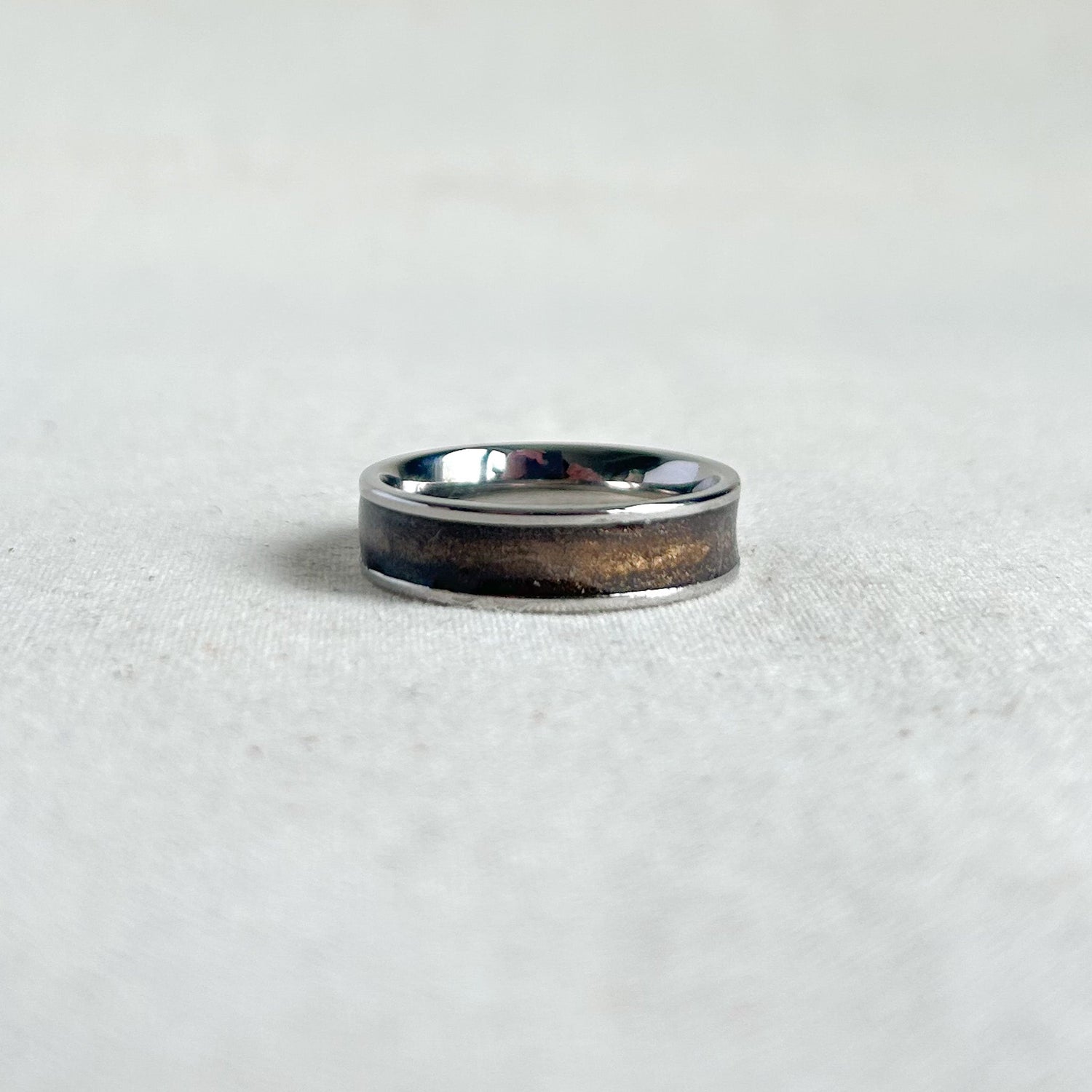 Silver ring with bronze inlay on a grey background