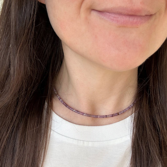 Close-up of a person wearing a delicate necklace with small beads.