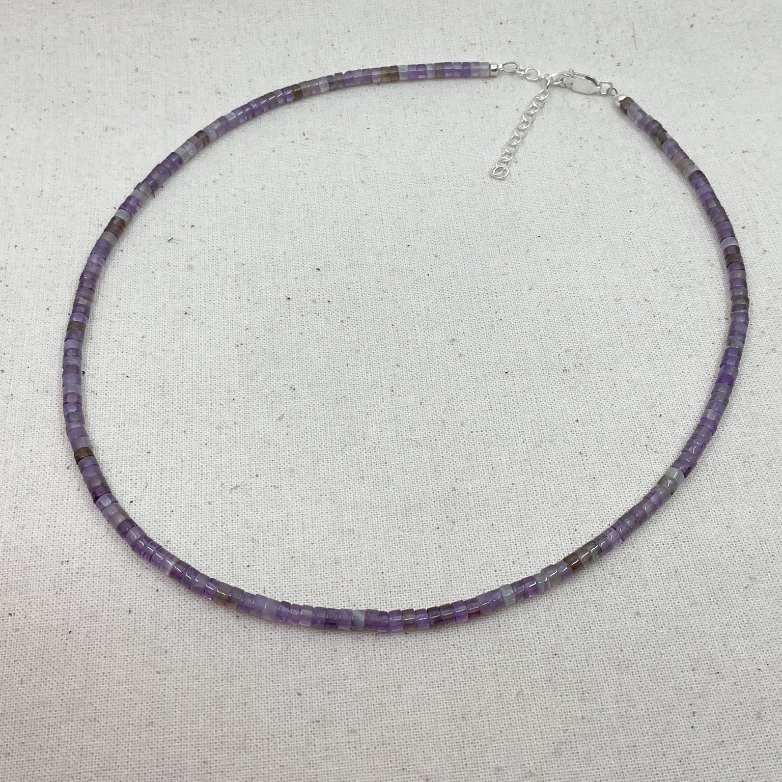 Purple beaded necklace on a light gray background