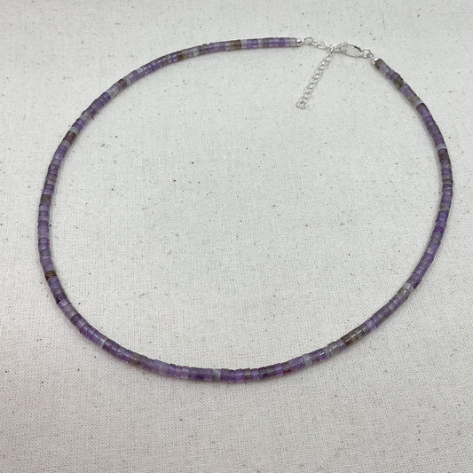 Purple beaded necklace on a light gray background