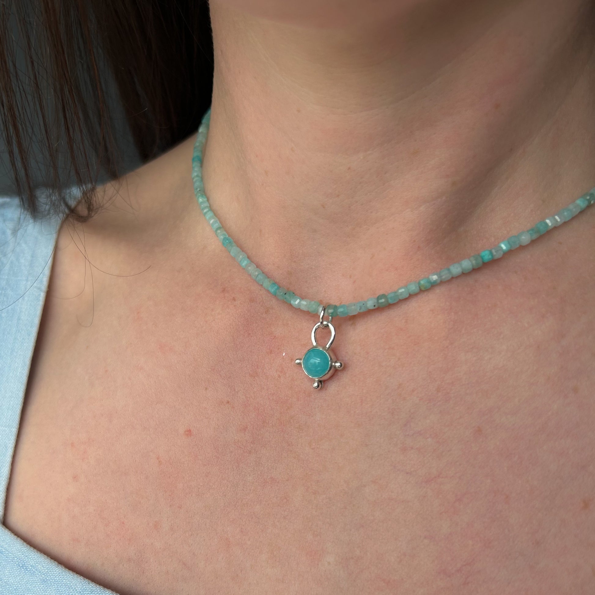Necklace with a turquoise pendant worn by a person