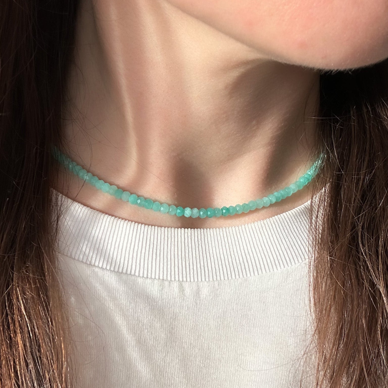 Close-up of a person wearing a turquoise beaded necklace.