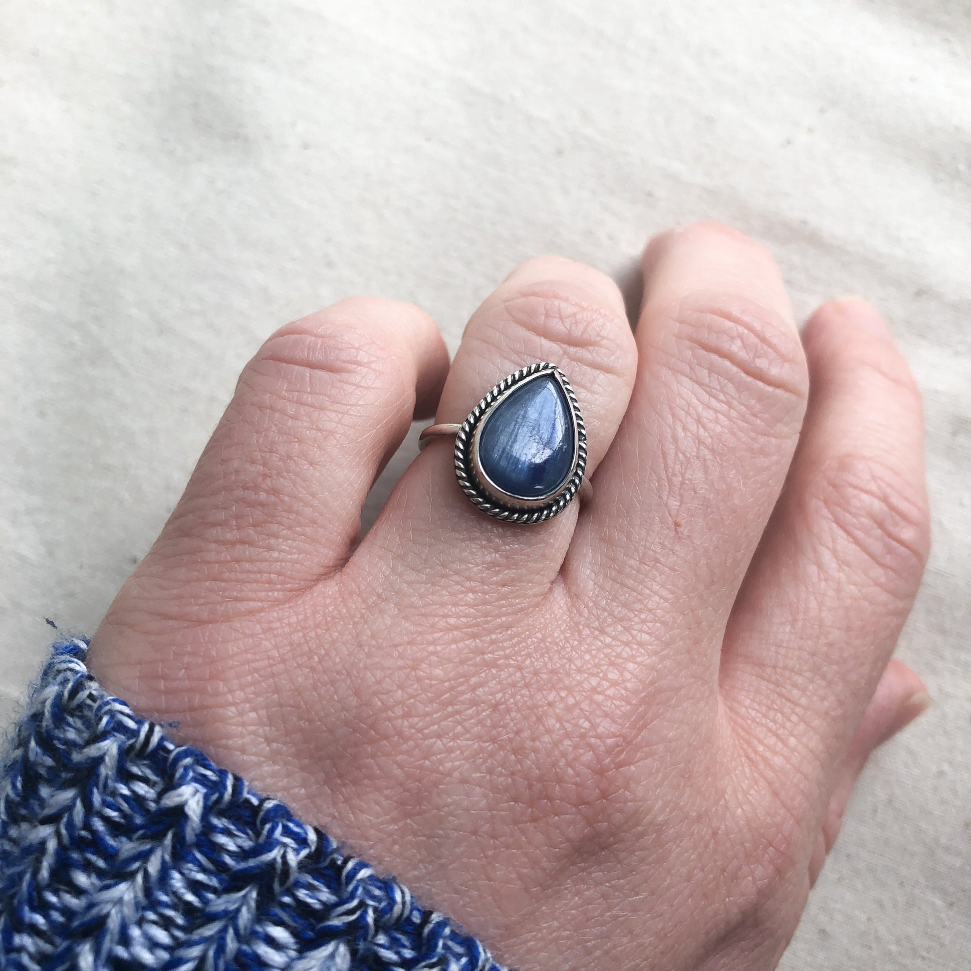 Blue kyanite sing with sterling silver band and twisted border on model's hand
